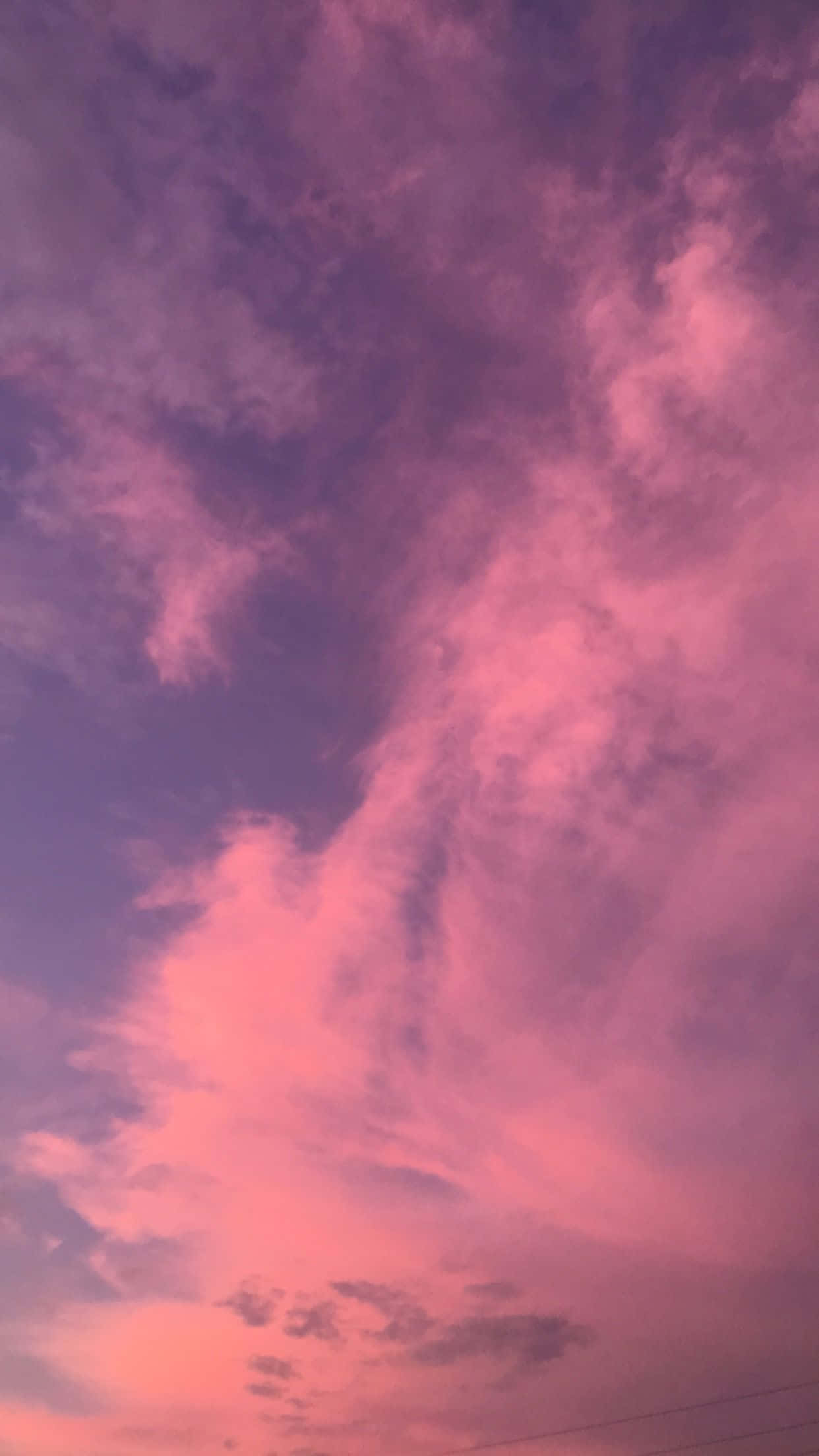 桌布 壁紙 — 黃昏時分，雲彩翻騰，天空被塗上鮮豔的粉紅色和紫色，景象壯麗。