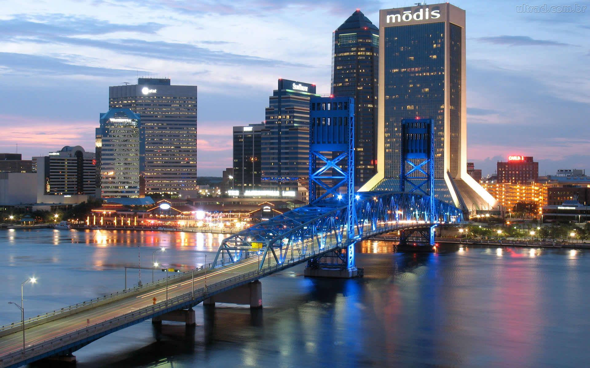 Jacksonville 桌布 壁紙 — 黃昏時分充滿活力的城市天際線，一座發光的藍色橋樑橫跨反射的河流。