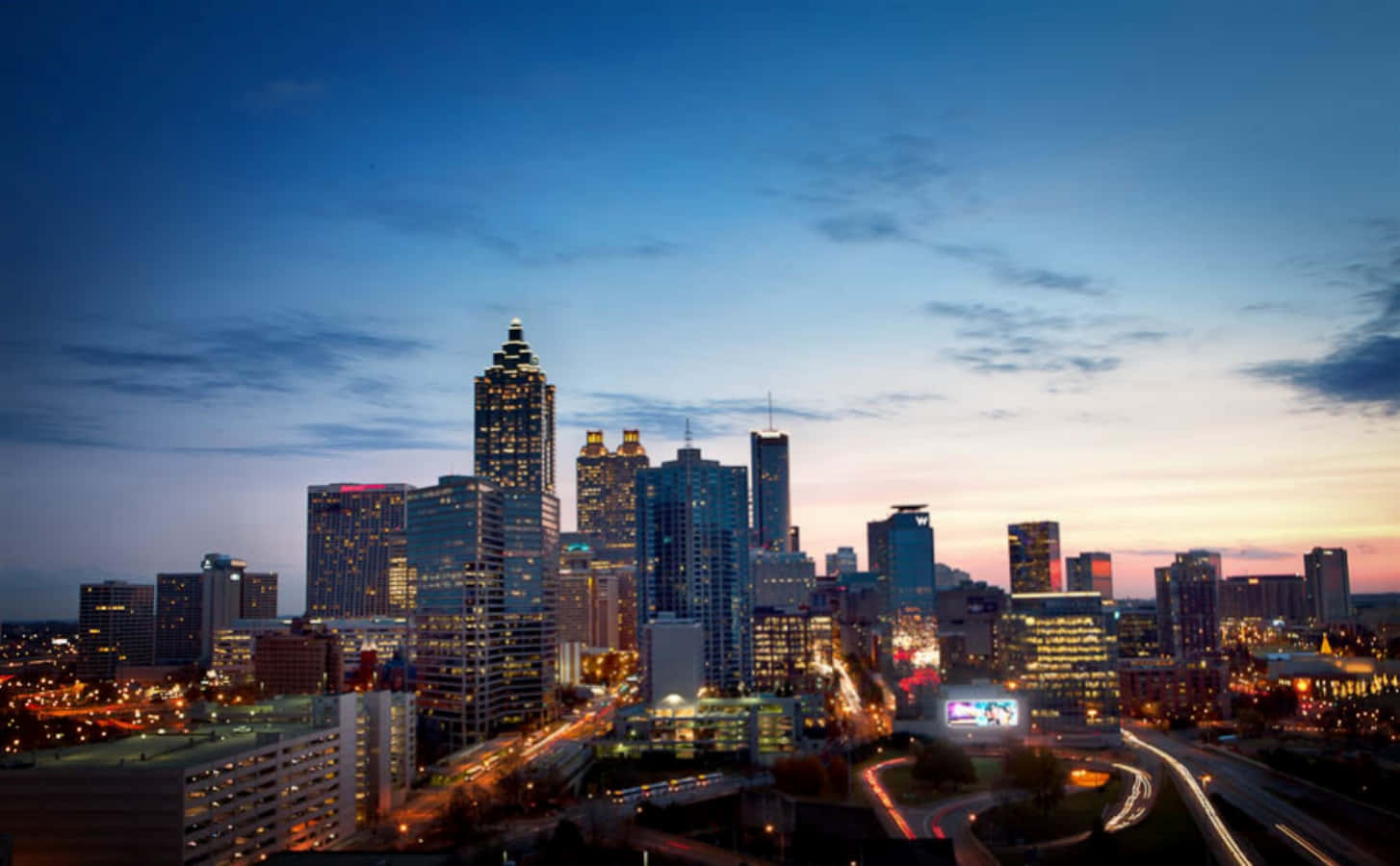 Atlanta Georgia 桌布 壁紙 — 黃昏時分充滿活力的城市天際線，摩天大樓燈火通明，街燈閃爍，映襯著漸變的天空。