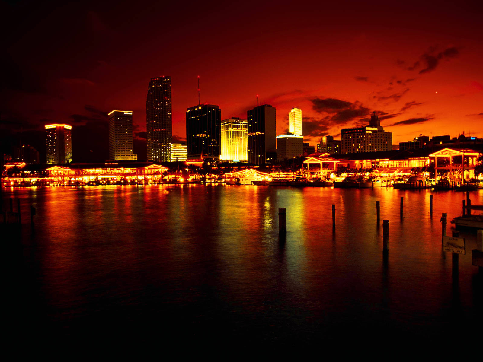 洛杉磯 桌布 壁紙 — 黃昏時分充滿活力的城市天際線，火紅的橙紅色天空倒映在下方平靜的水面上。