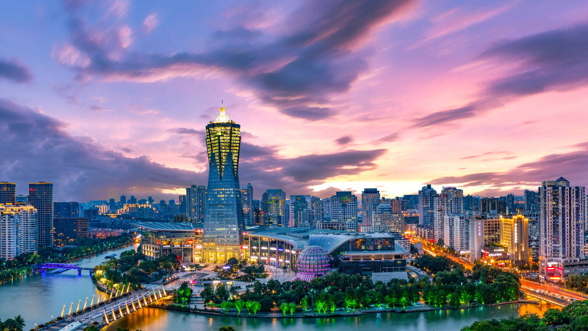 Hangzhou 桌布 壁紙 — 黃昏時分充滿活力的城市天際線，發光的摩天大樓和河流映照出粉紫色的雲彩。
