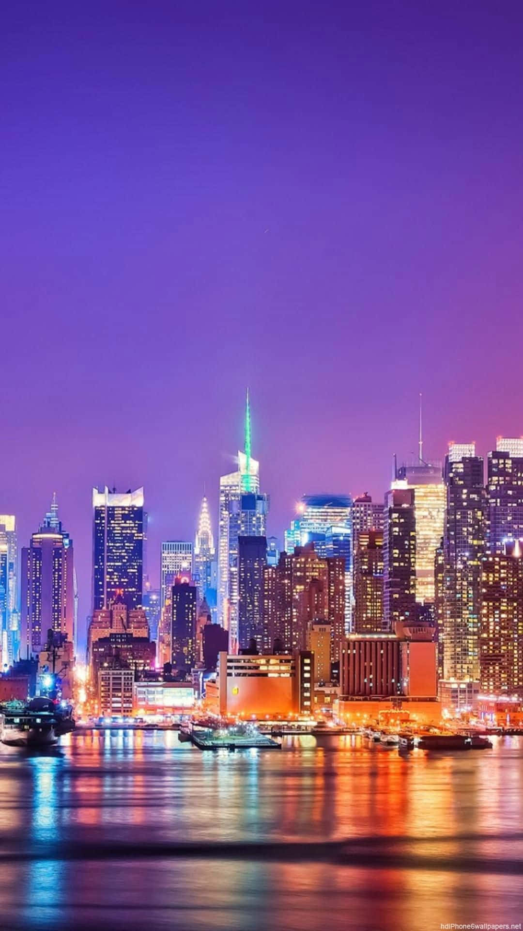美學 桌布 壁紙 — 黃昏時分充滿活力的城市天際線，閃爍的摩天大樓倒映在下方平靜的水面上。