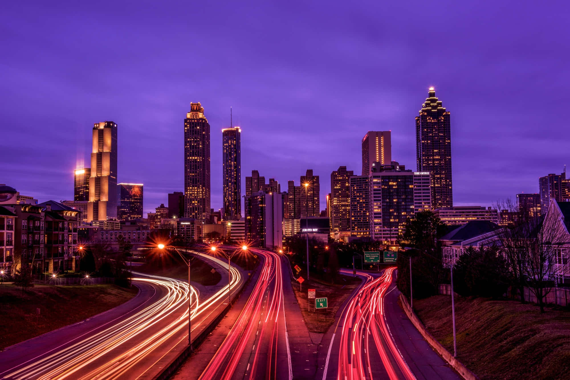 Atlanta Georgia 桌布 壁紙 — 黃昏時分充滿活力的城市天際線，閃爍的摩天大樓和蜿蜒高速公路上拖曳的紅色交通燈光。