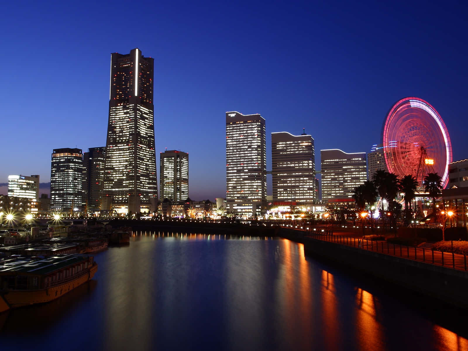 Tokyo Night 桌布 壁紙 — 黃昏時分充滿活力的城市天際線，閃爍的摩天大樓和紅色摩天輪倒映在平靜的水面上。