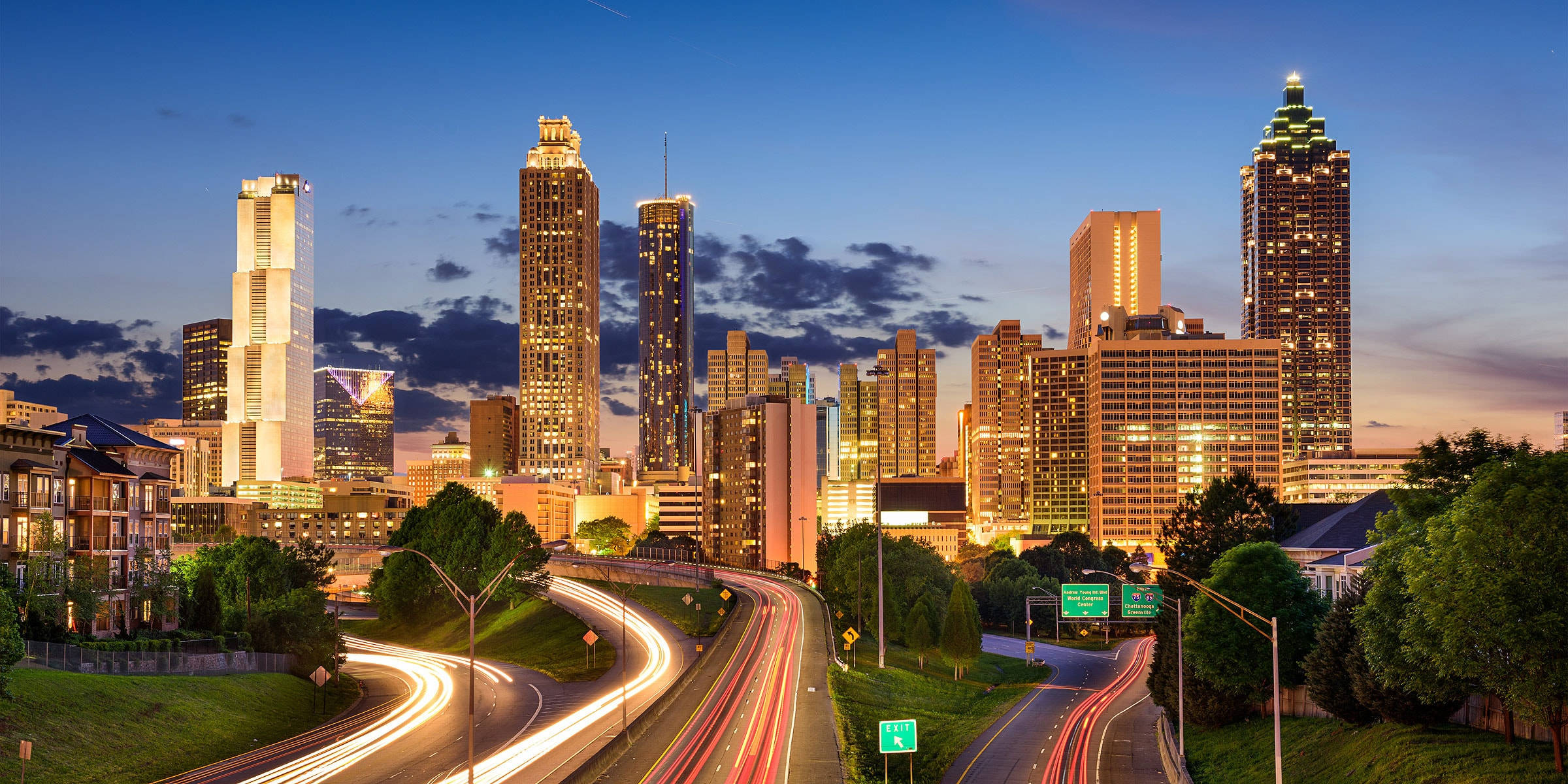 Atlanta 桌布 壁紙 — 黃昏時分充滿活力的城市天際線，閃爍的摩天大樓和蜿蜒高速公路上的車流光跡。