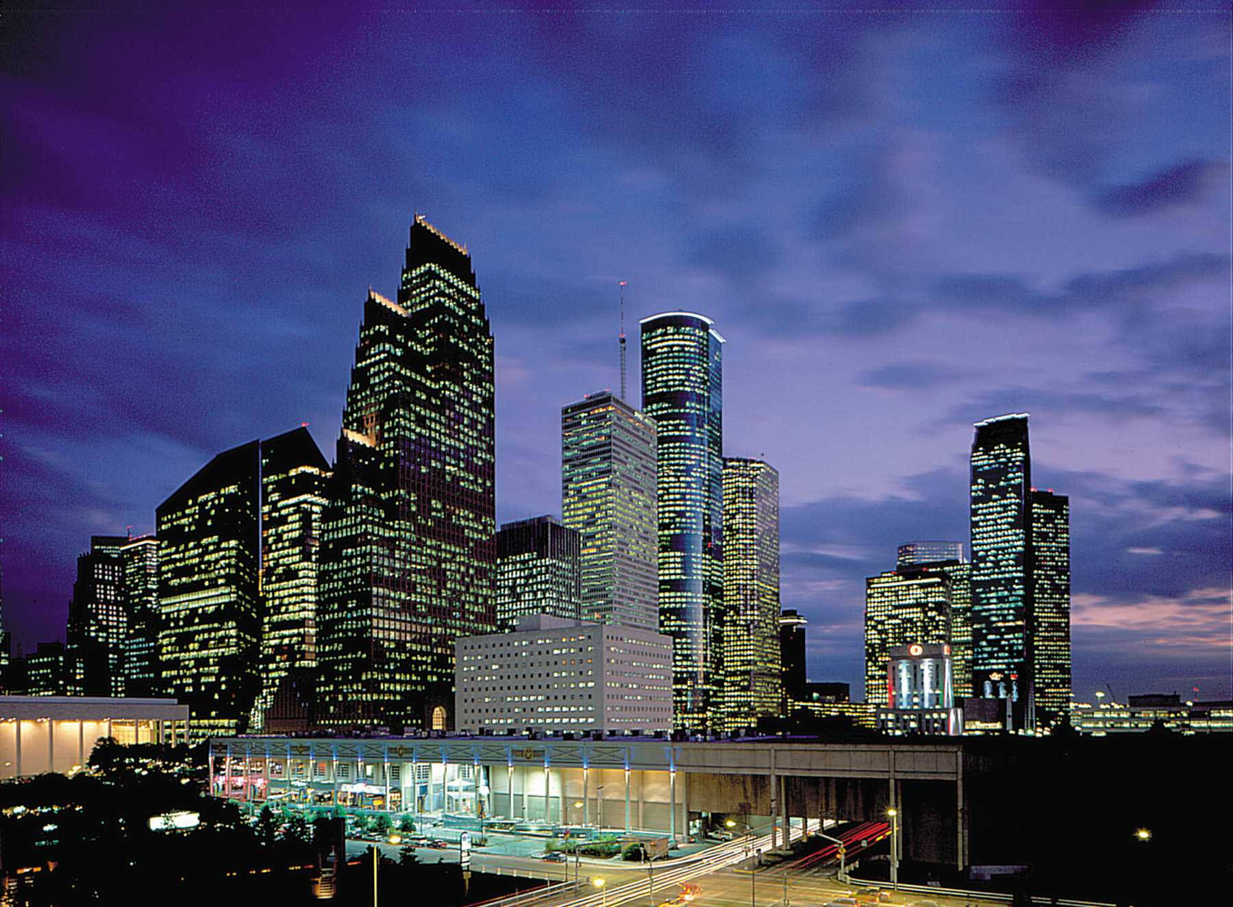 Houston 桌布 壁紙 — 黃昏時分充滿活力的城市天際線，高聳的摩天大樓在深紫色天空下閃耀。