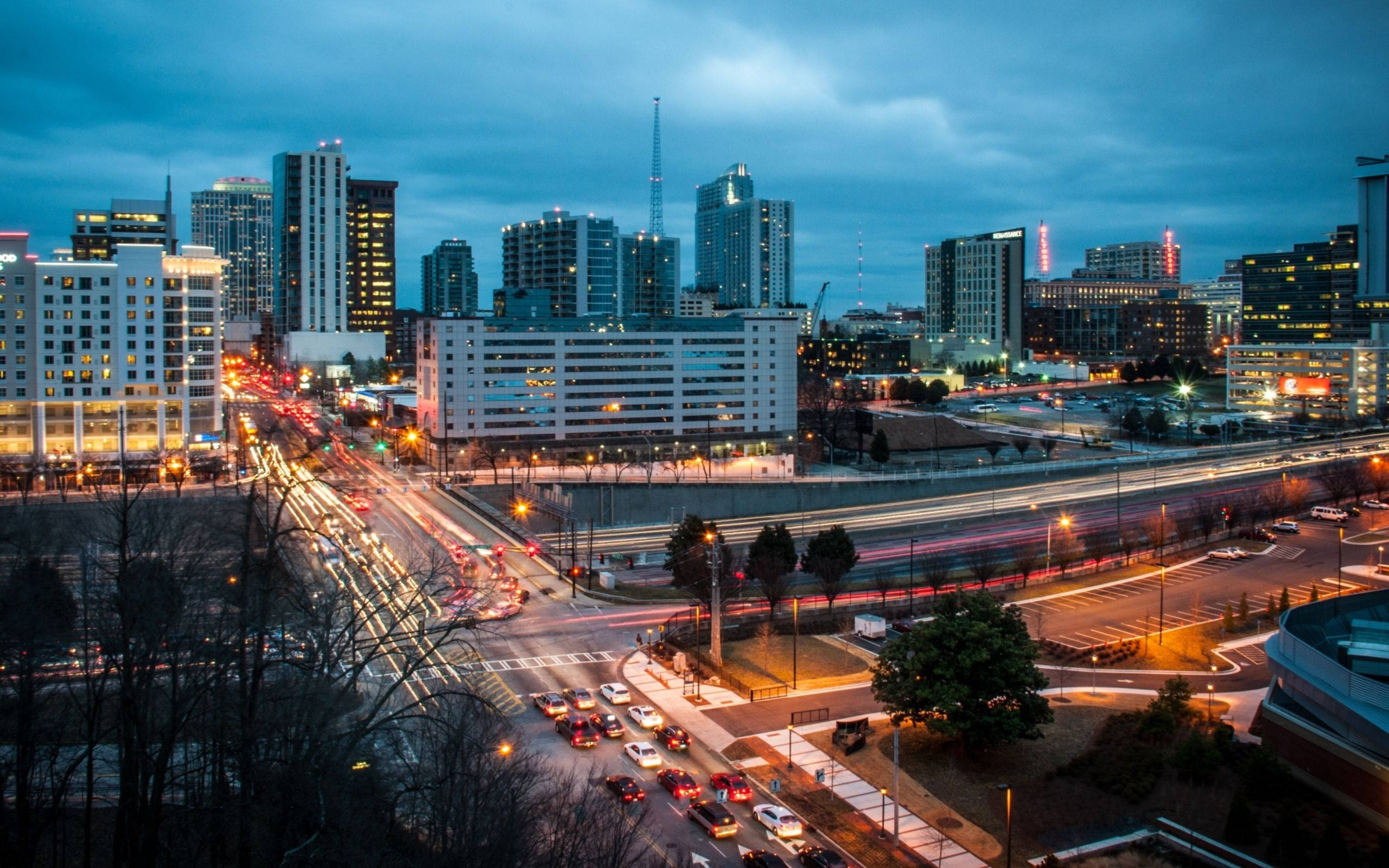 Atlanta 桌布 壁紙 — 黃昏時分充滿活力的城市景觀，在憂鬱的藍天下，汽車燈光劃過，摩天大樓燈火通明。