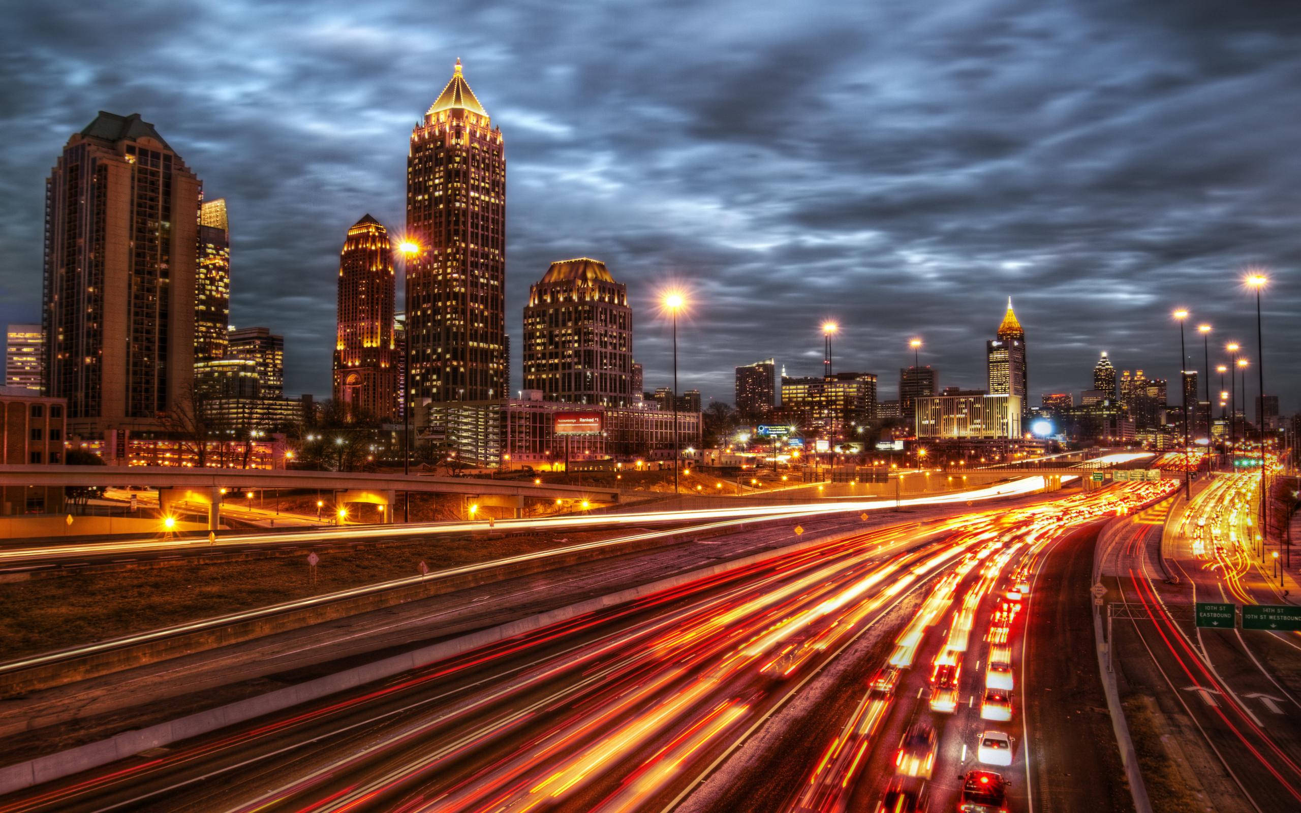 Atlanta 桌布 壁紙 — 黃昏時分充滿活力的城市景觀，在燈火通明的摩天大樓下的高速公路上，汽車燈光形成流動的光軌。