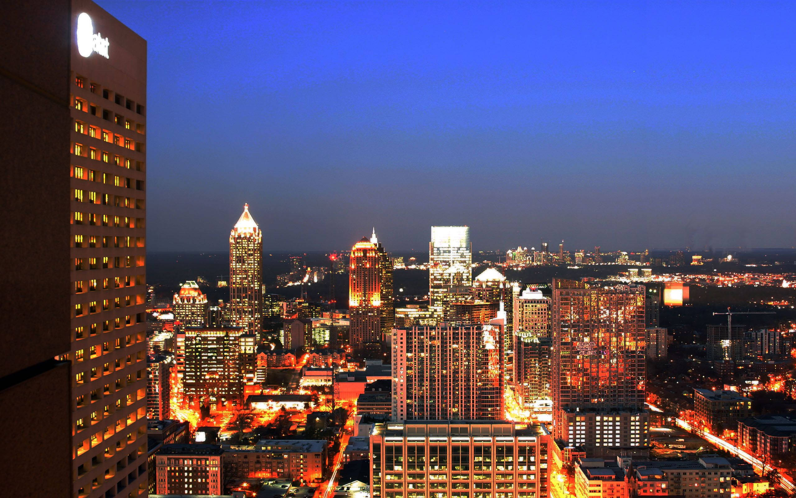 Atlanta 桌布 壁紙 — 黃昏時分充滿活力的城市景觀，摩天大樓在深藍色天空的映襯下閃閃發光。