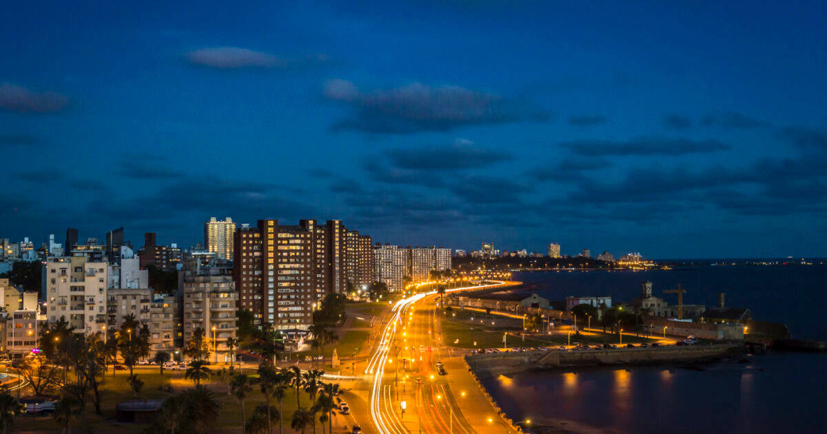 South America 桌布 壁紙 — 黃昏時分充滿活力的城市景觀，發光的街燈沿著海濱道路延伸，映襯著深藍色的天空。