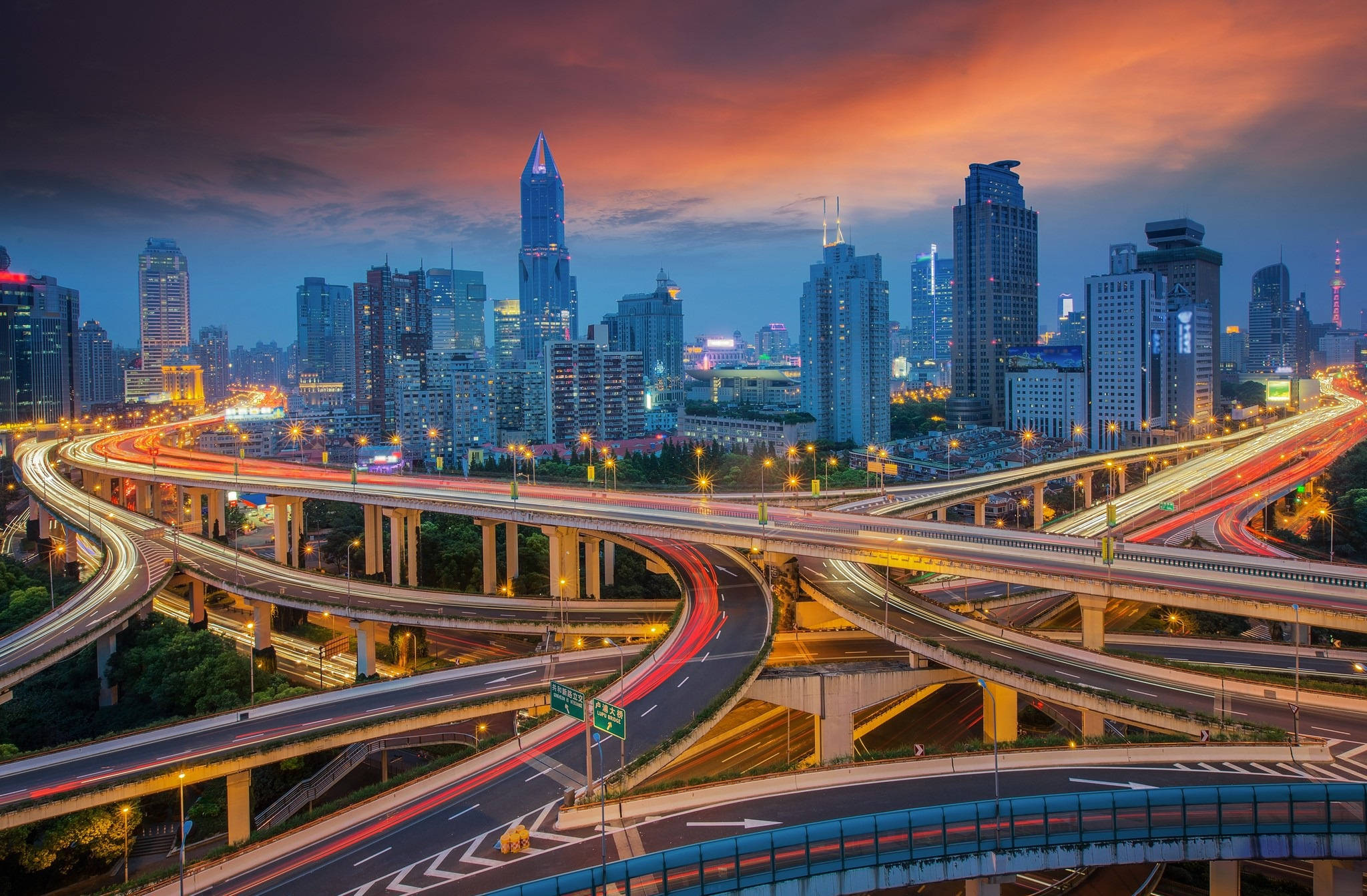 Shanghai 桌布 壁紙 — 黃昏時分充滿活力的城市景觀，閃爍的摩天大樓和複雜的高架高速公路上的車流光跡。