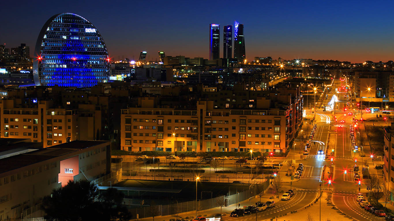 Madrid 桌布 壁紙 — 黃昏時分充滿活力的城市景觀，閃爍的摩天大樓和下方燈火通明的街道。
