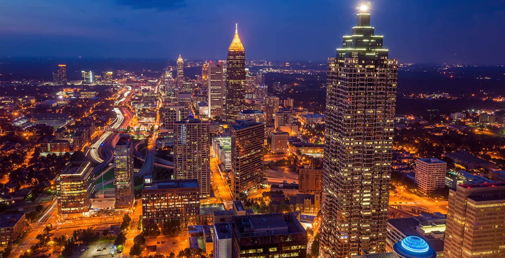 Atlanta Georgia 桌布 壁紙 — 黃昏時分充滿活力的城市景觀鳥瞰圖，高樓大廈燈火通明，道路閃爍發光。