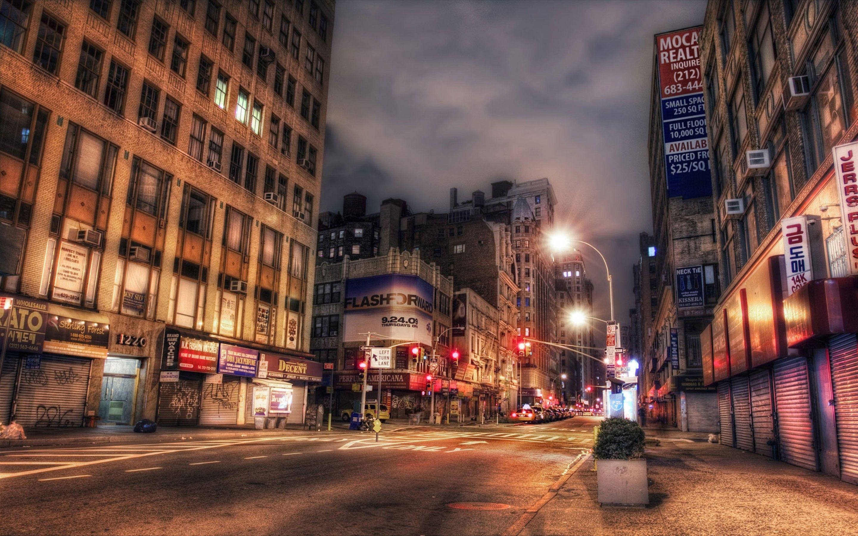 Broadway 桌布 壁紙 — 黃昏時分充滿活力的城市街道，閃爍的霓虹燈招牌和溫暖的路燈照亮了高樓大廈和關閉的商店門面。
