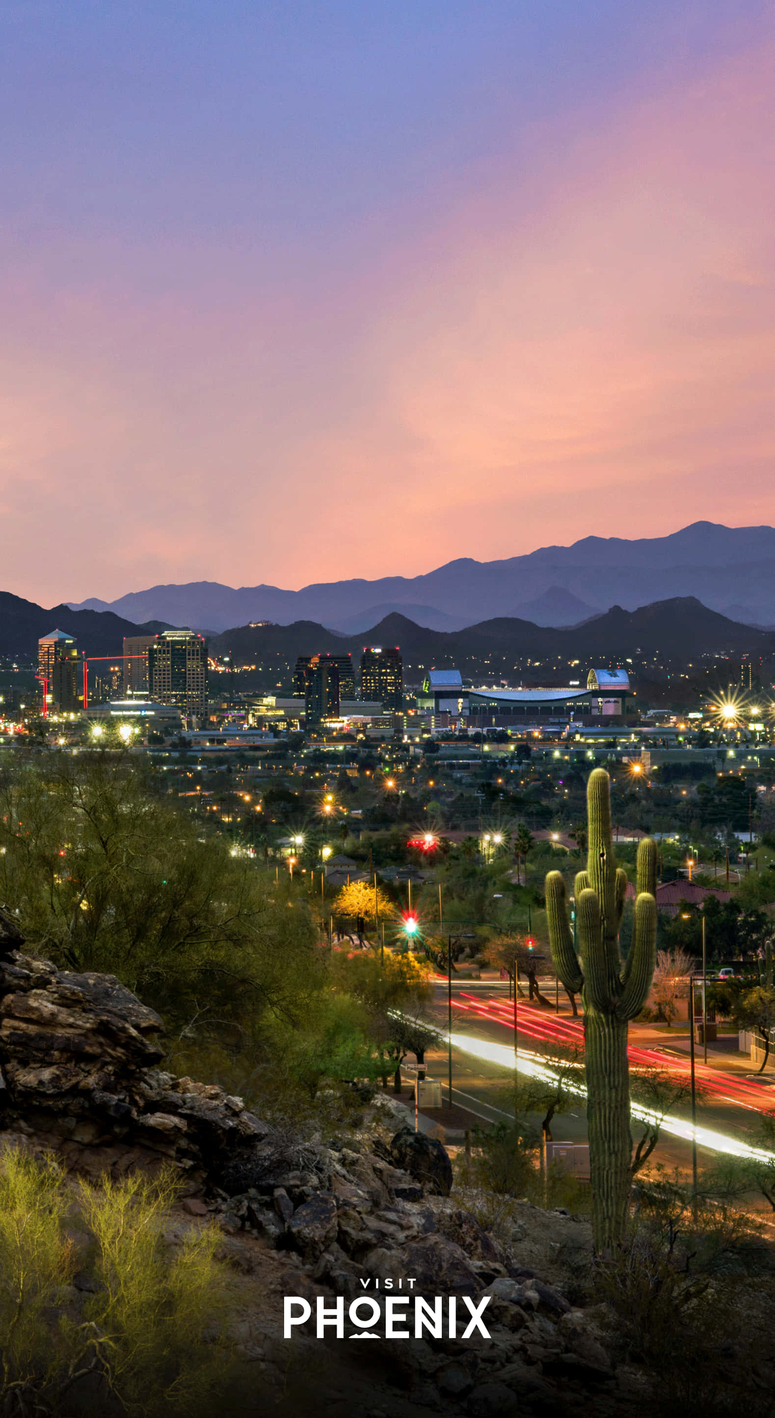Phoenix Arizona 桌布 壁紙 — 黃昏時分充滿活力的沙漠城市景觀，閃爍的燈光、遠山和前景中突出的薩瓜羅仙人掌。