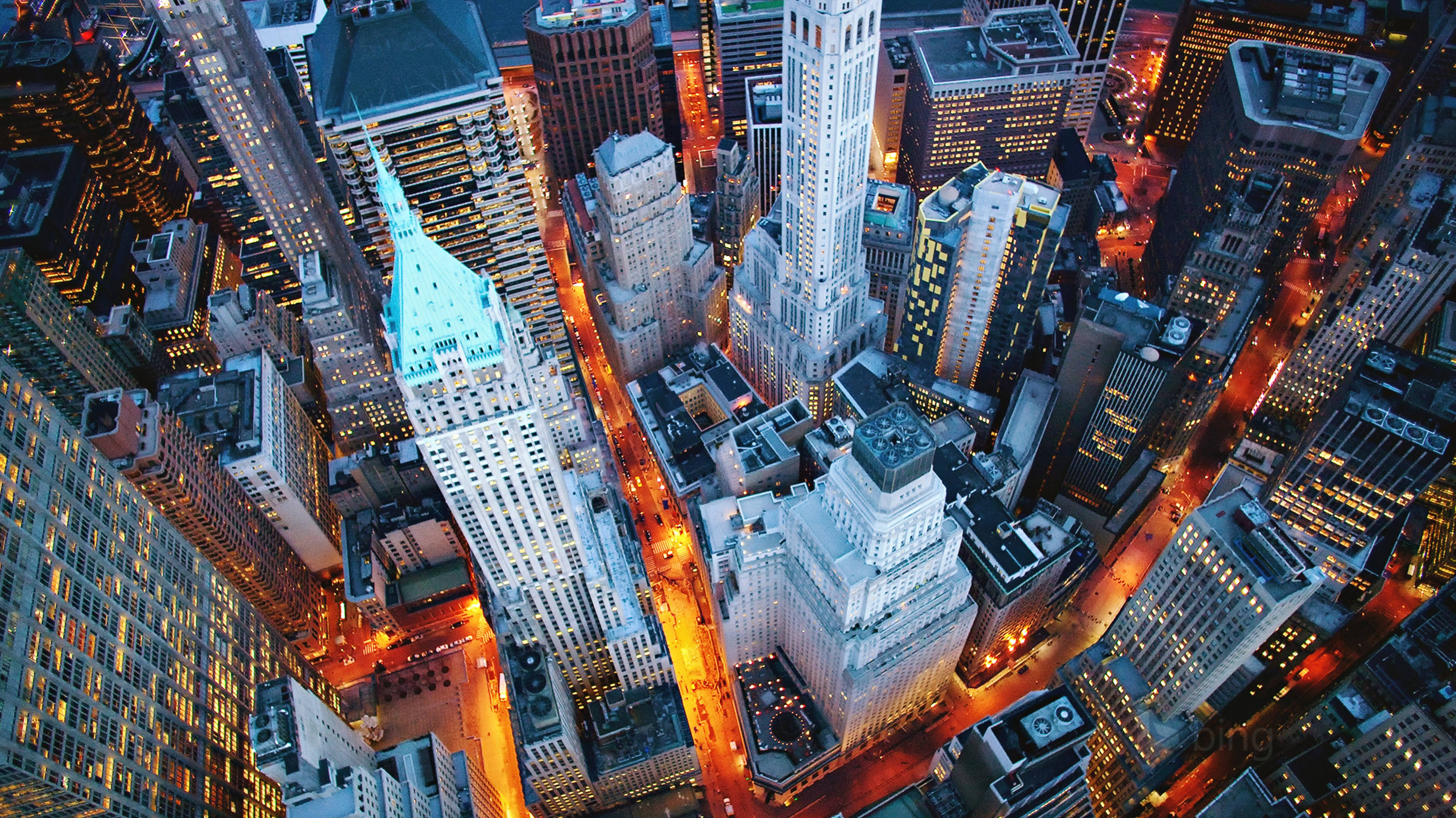 New York 桌布 壁紙 — 黃昏時分密集城市景觀中，燈火通明的摩天大樓和發光街道的鳥瞰圖。