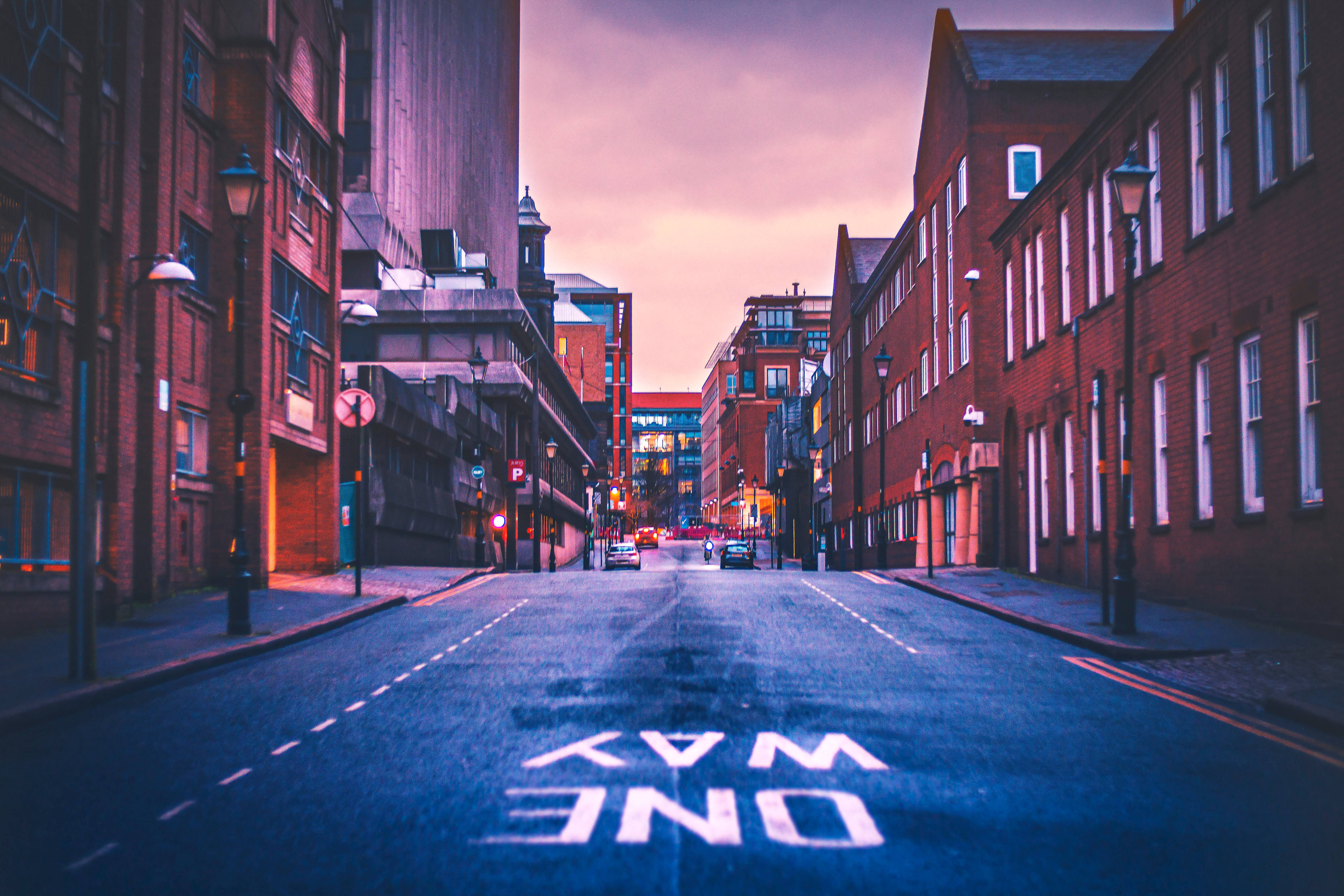 Birmingham 桌布 壁紙 — 黃昏時分寧靜的城市街道，兩旁是磚砌建築，瀝青上繪有發光的單行道標誌。