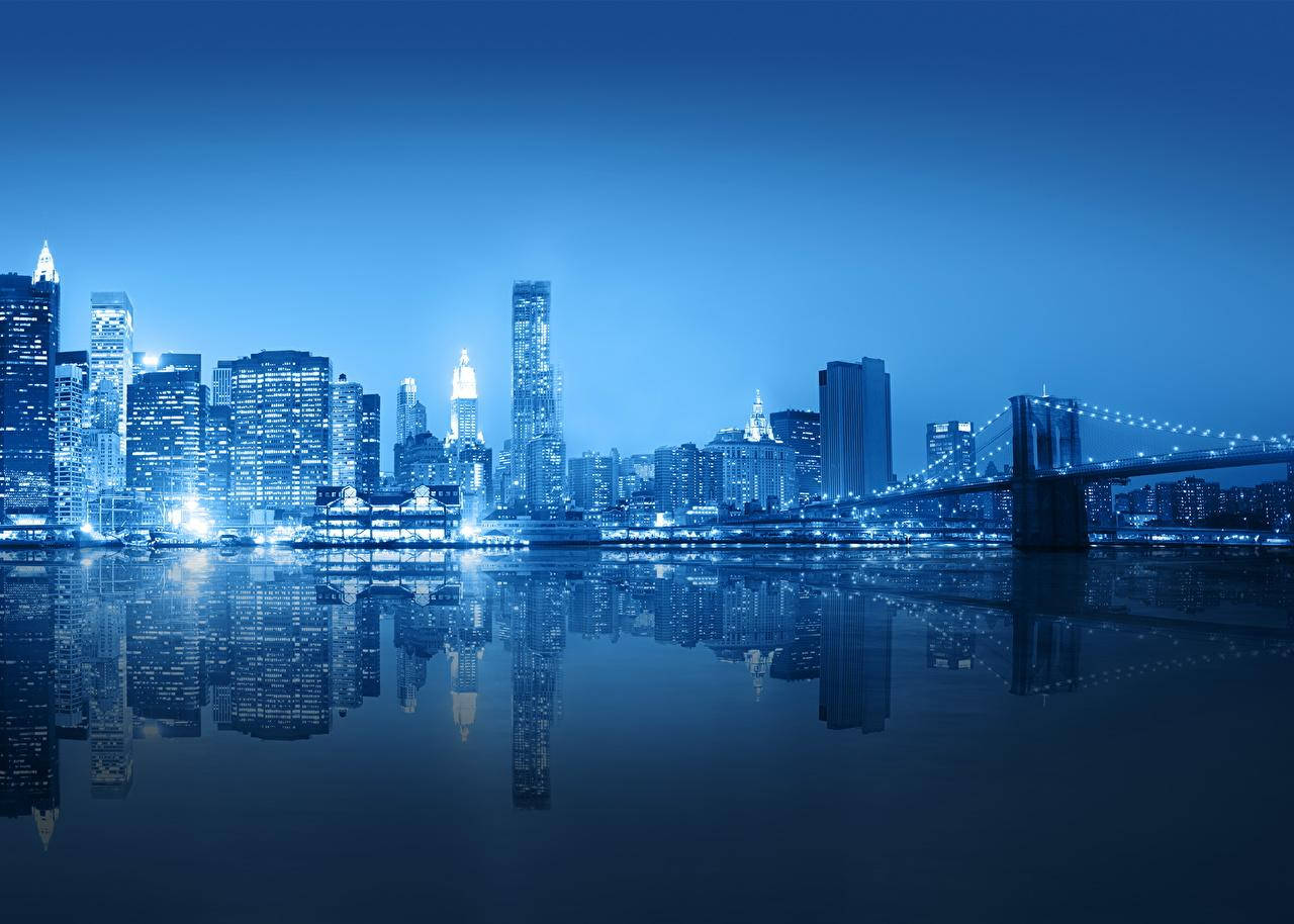 Nyc Aesthetic 桌布 壁紙 — 黃昏時分寧靜的藍調城市景觀，摩天大樓和橋樑倒映在平靜的水面上。