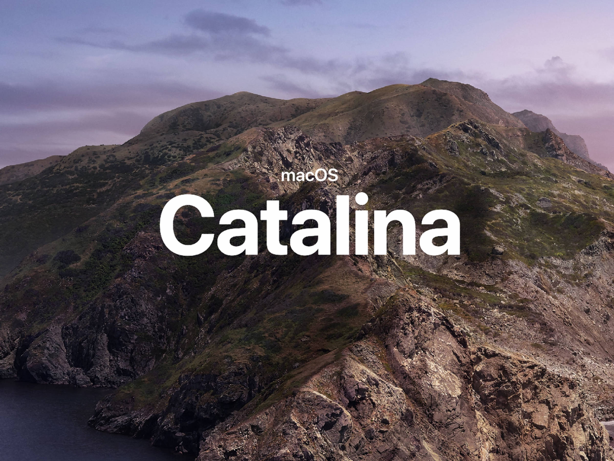 Catalina 桌布 壁紙 — 黃昏時分崎嶇的山區海岸線，帶有柔和的紫色和藍色天空，並覆蓋了 macOS Catalina 文字。