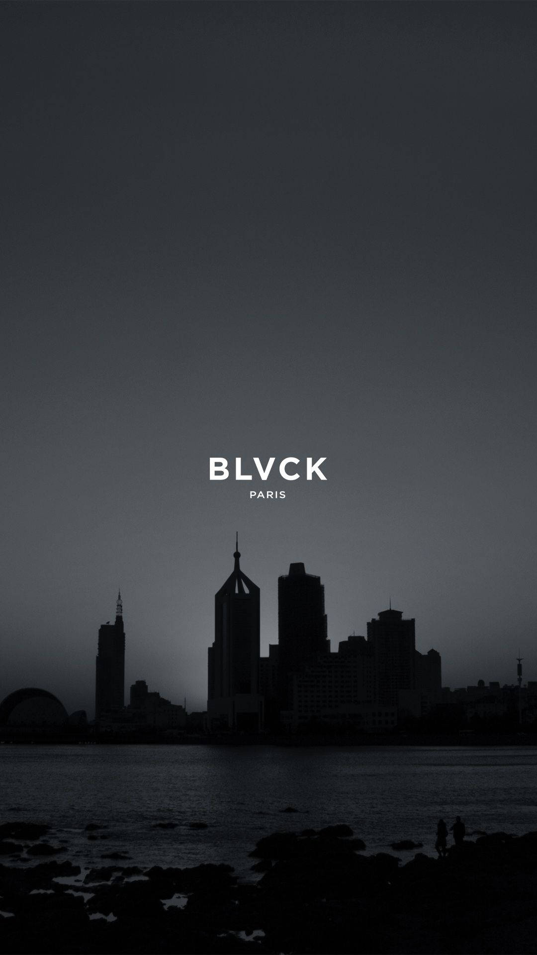 Skyscraper 桌布 壁紙 — 黃昏時分巴黎天際線的剪影，兩人在平靜水邊的岩石岸上站立。