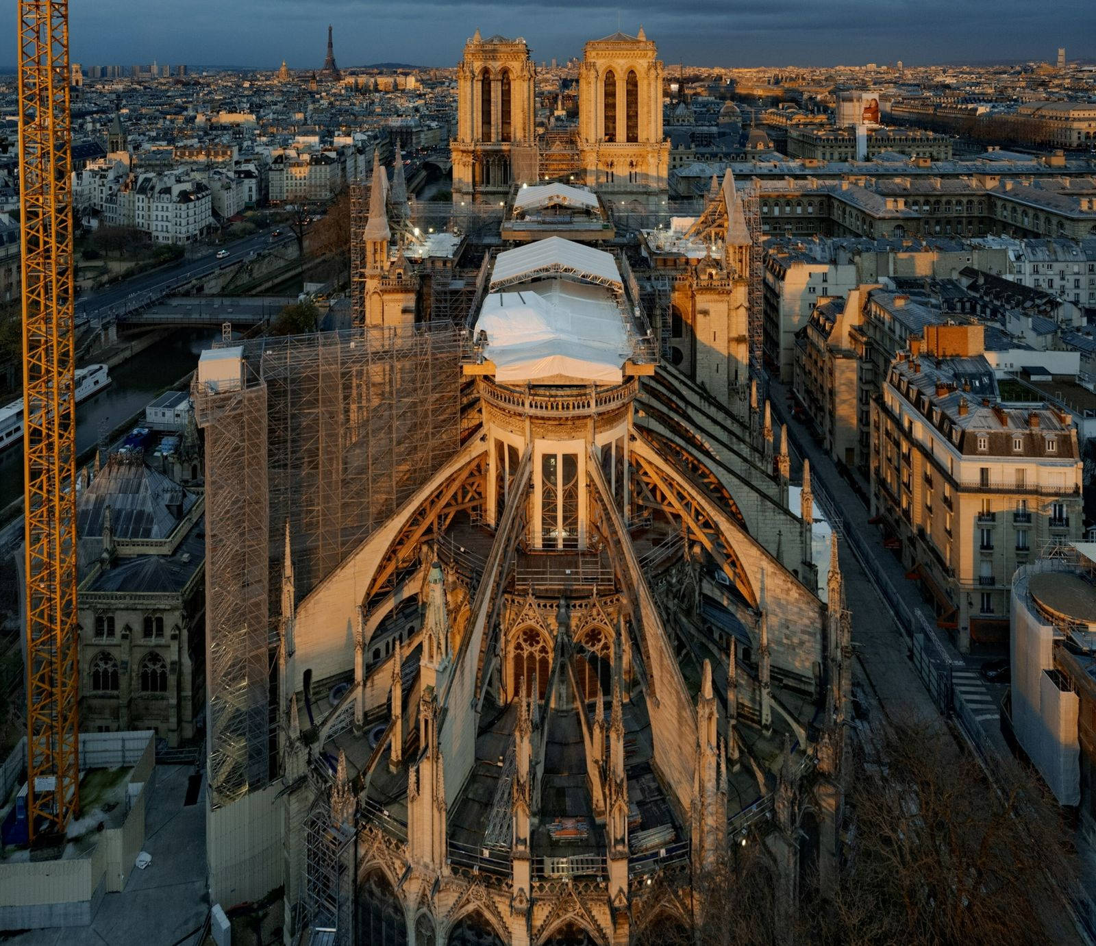 Notre Dame 桌布 壁紙 — 黃昏時分巴黎聖母院的鳥瞰圖，金色光線照亮其哥德式建築及周圍的城市景觀。