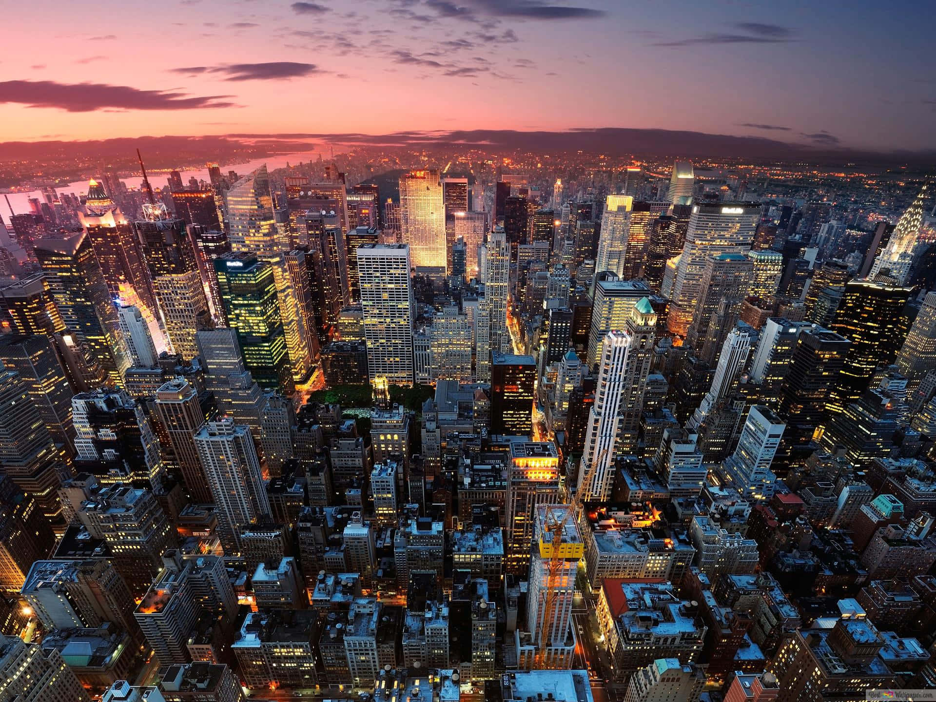 New York City Landscape 桌布 壁紙 — 黃昏時分廣闊城市景觀的鳥瞰圖，摩天大樓在粉紅色和紫色的天空中閃耀。