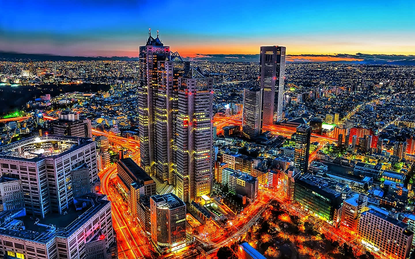 Buildings 桌布 壁紙 — 黃昏時分廣闊城市景觀的鳥瞰圖，閃爍的摩天大樓和流動的交通燈光。