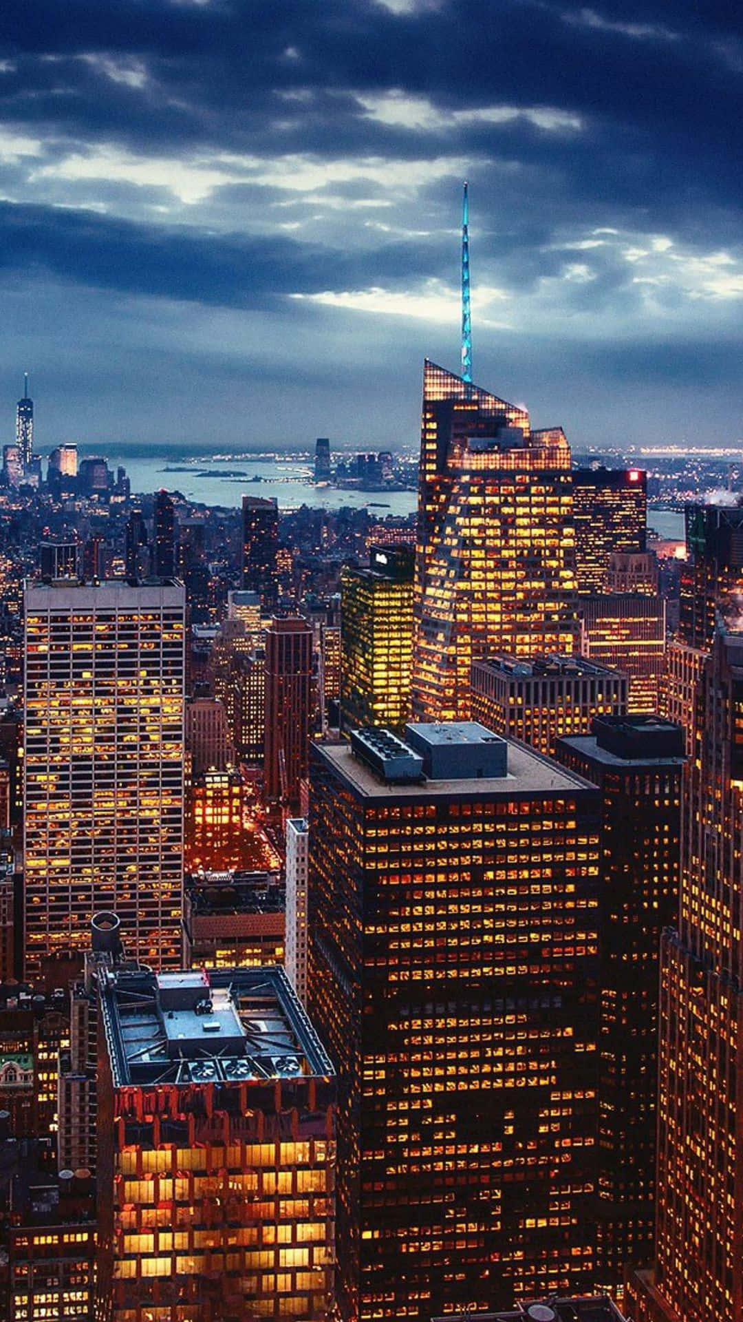 Android Ny City 桌布 壁紙 — 黃昏時分廣闊城市景觀的鳥瞰圖，高聳的摩天大樓在憂鬱的藍天下溫暖地發光。