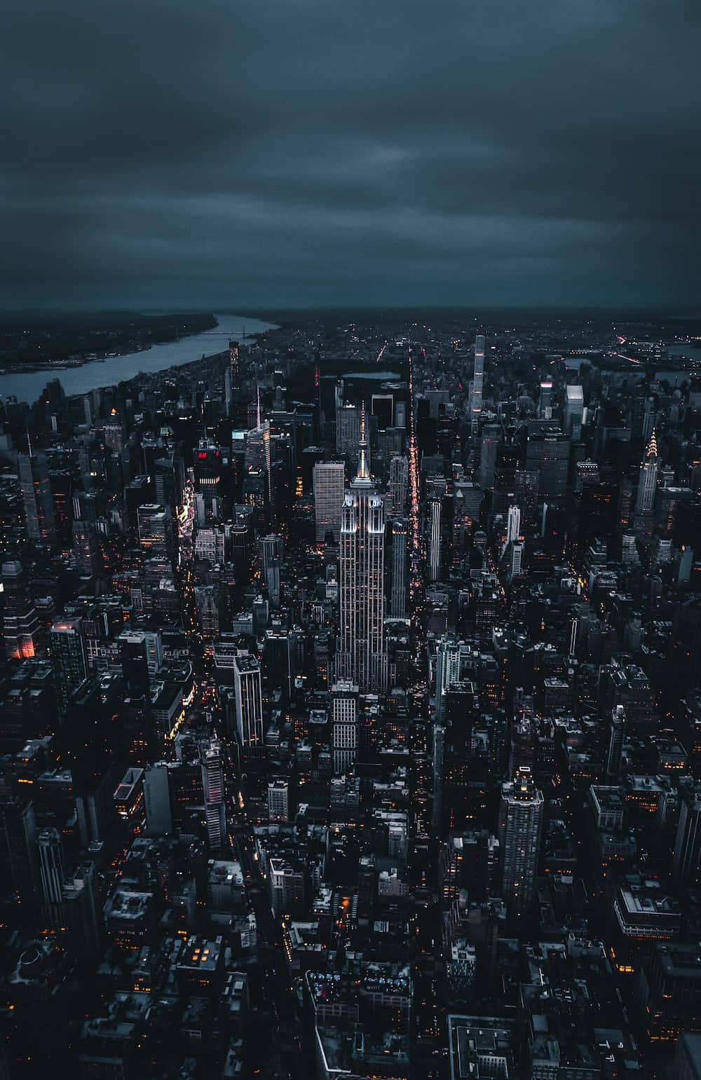 Night Time 桌布 壁紙 — 黃昏時分廣闊城市景觀的鳥瞰圖，高聳的摩天大樓在陰沉的灰色天空下閃耀。