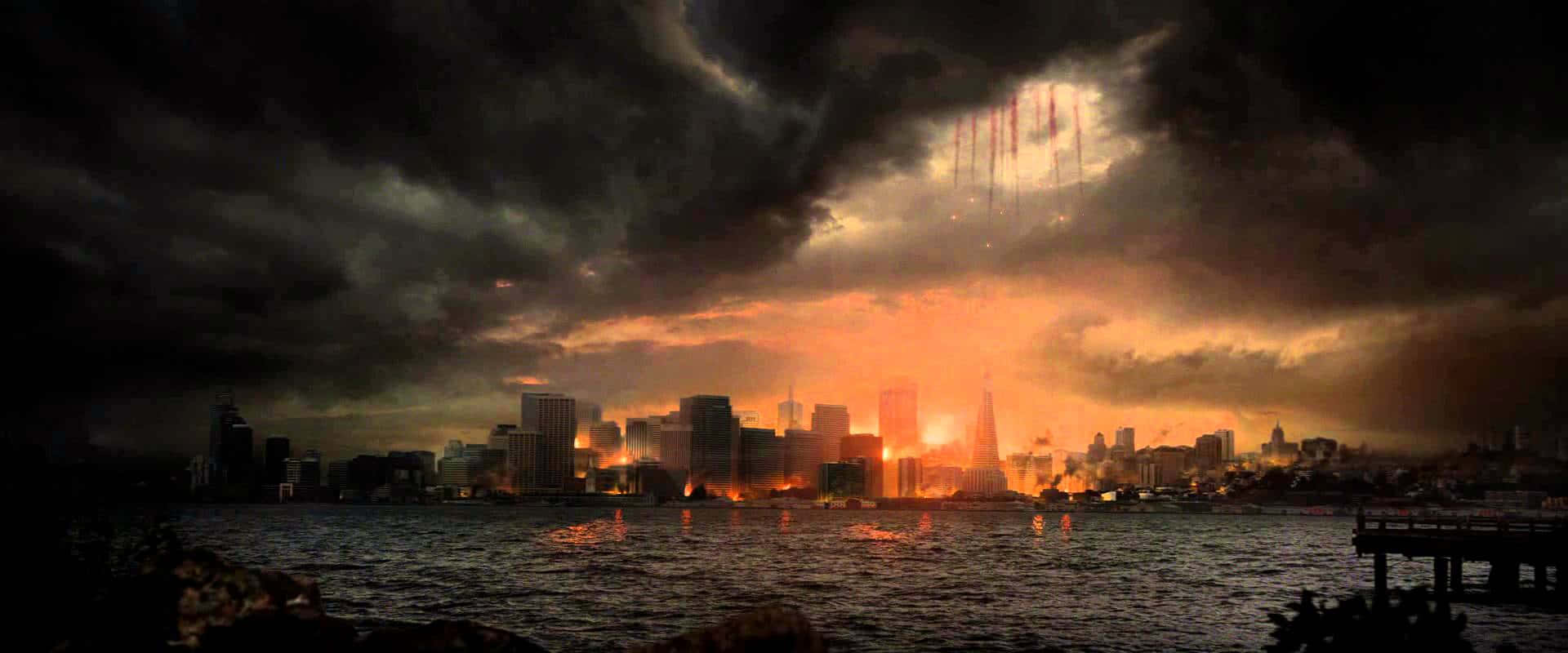Godzilla 2014 桌布 壁紙 — 黃昏時分戲劇性的城市天際線，伴隨著火熱的橙色爆炸和頭頂的黑暗暴風雲。