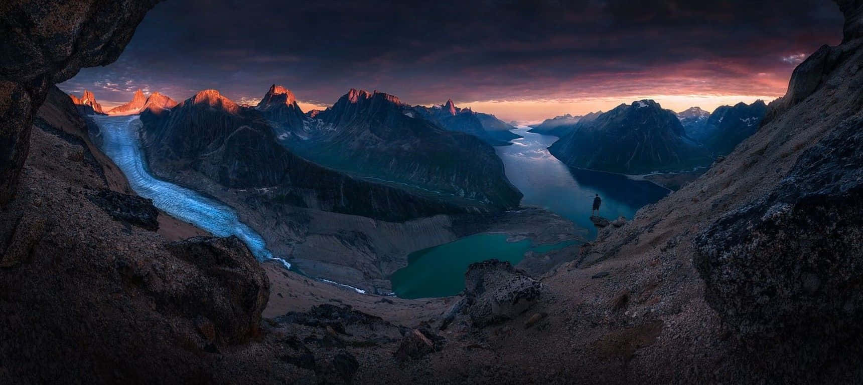 Greenland 桌布 壁紙 — 黃昏時分戲劇性的山景，發光的冰川蜿蜒穿過被岩石懸崖環繞的碧綠湖泊。