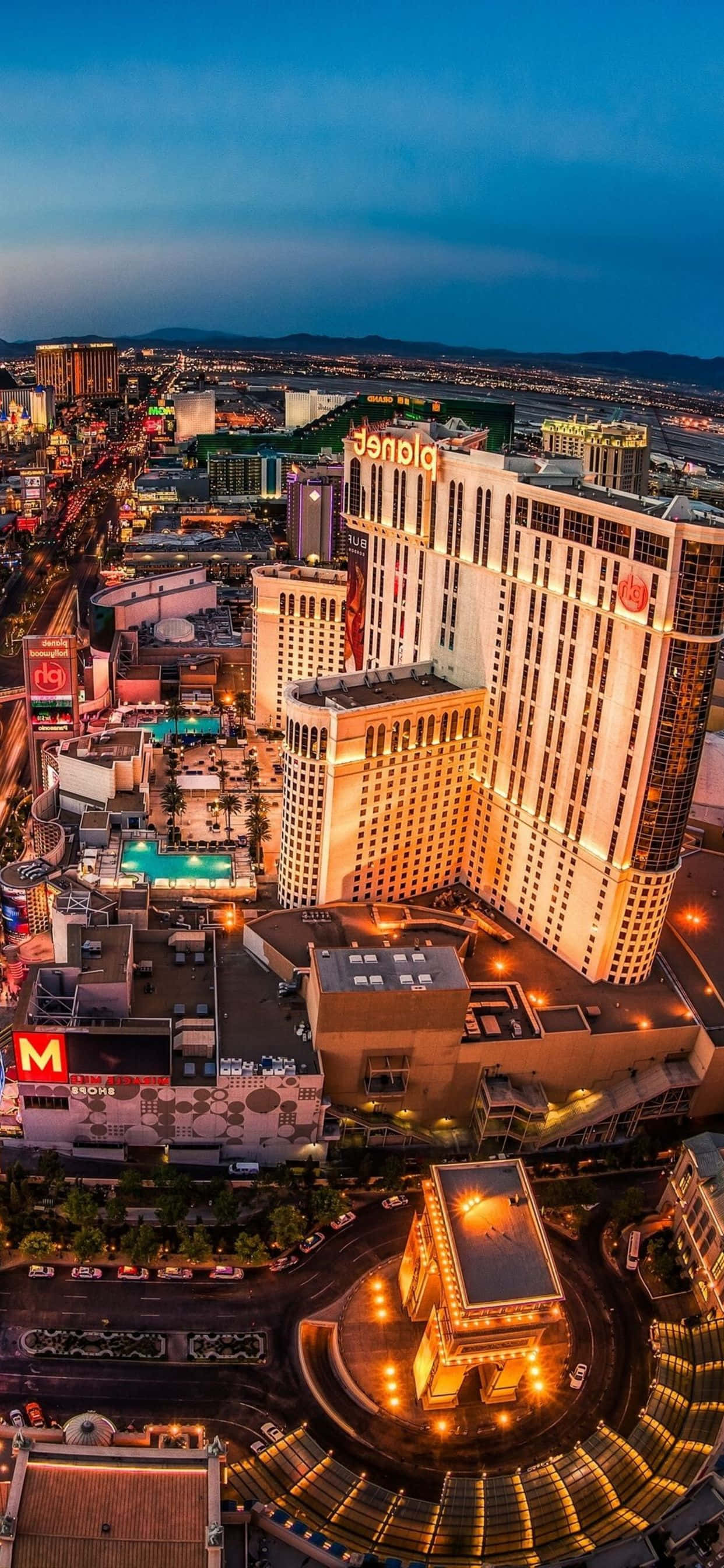 Las Vegas Phone 桌布 壁紙 — 黃昏時分拉斯維加斯大道的航拍景色，深藍色天空下燈火通明的酒店和繁忙的街道。