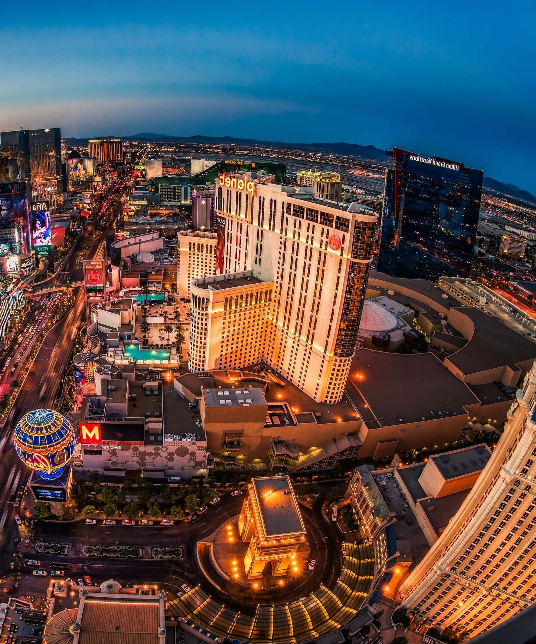Las Vegas Phone 桌布 壁紙 — 黃昏時分拉斯維加斯大道的航拍景色，閃爍的賭場酒店和繁忙的街道在下方。