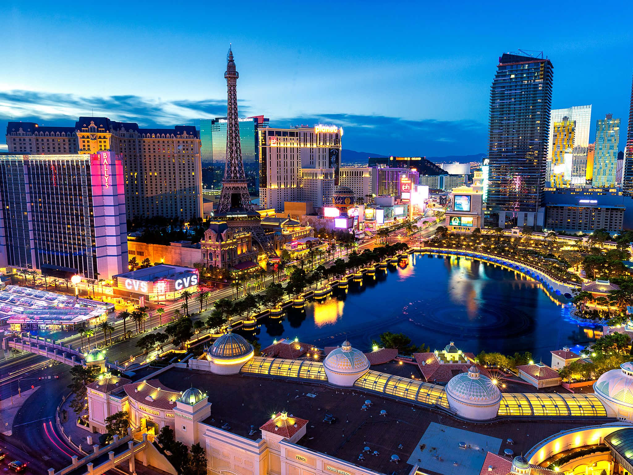 Las Vegas Skyline 桌布 壁紙 — 黃昏時分拉斯維加斯的鳥瞰圖，彎曲的水道和標誌性酒店上閃爍的霓虹燈倒影。