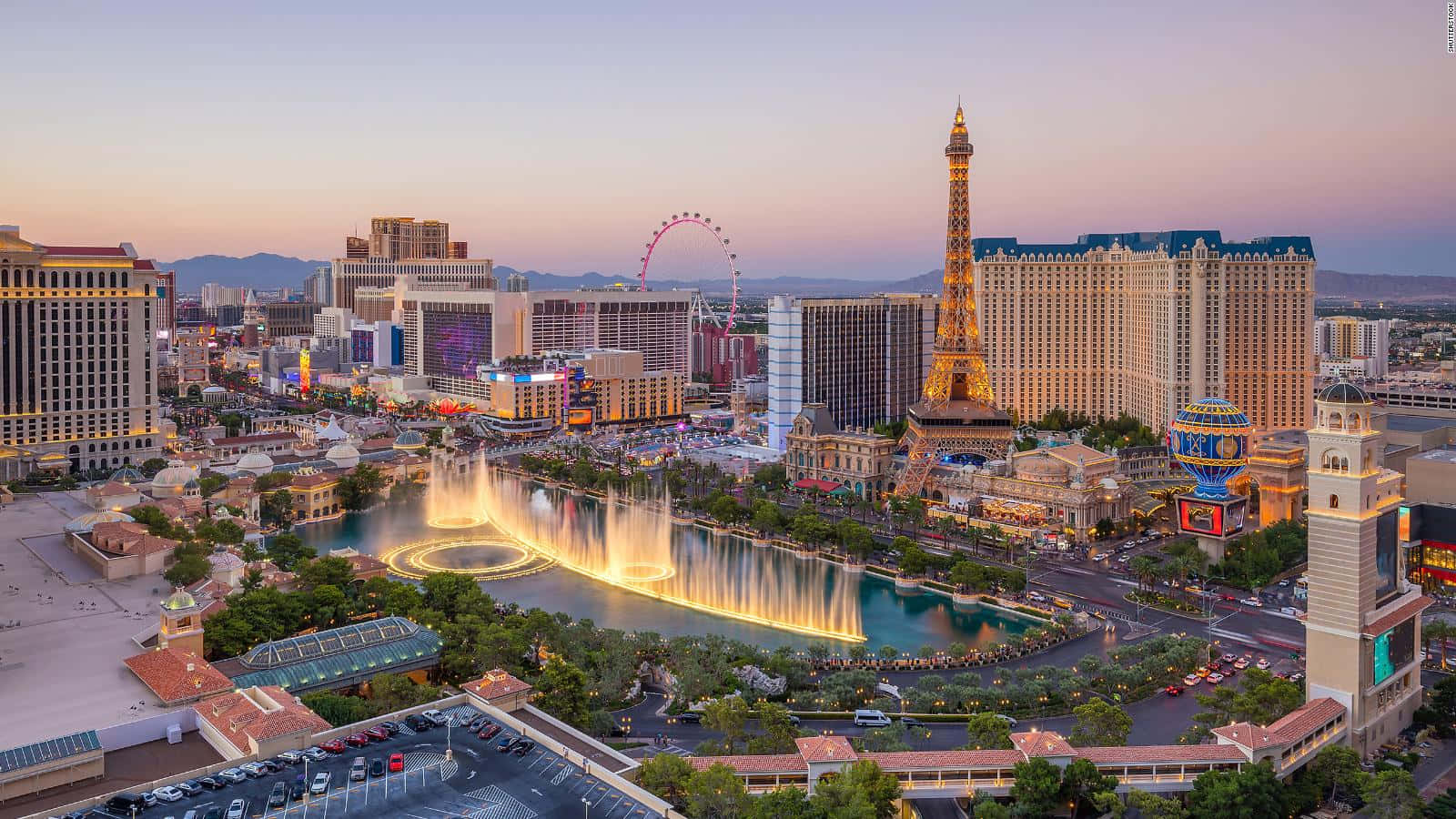 Las Vegas Skyline 桌布 壁紙 — 黃昏時分拉斯維加斯的鳥瞰圖，燈光璀璨的噴泉和複製的艾菲爾鐵塔在粉紅色天空下閃耀。