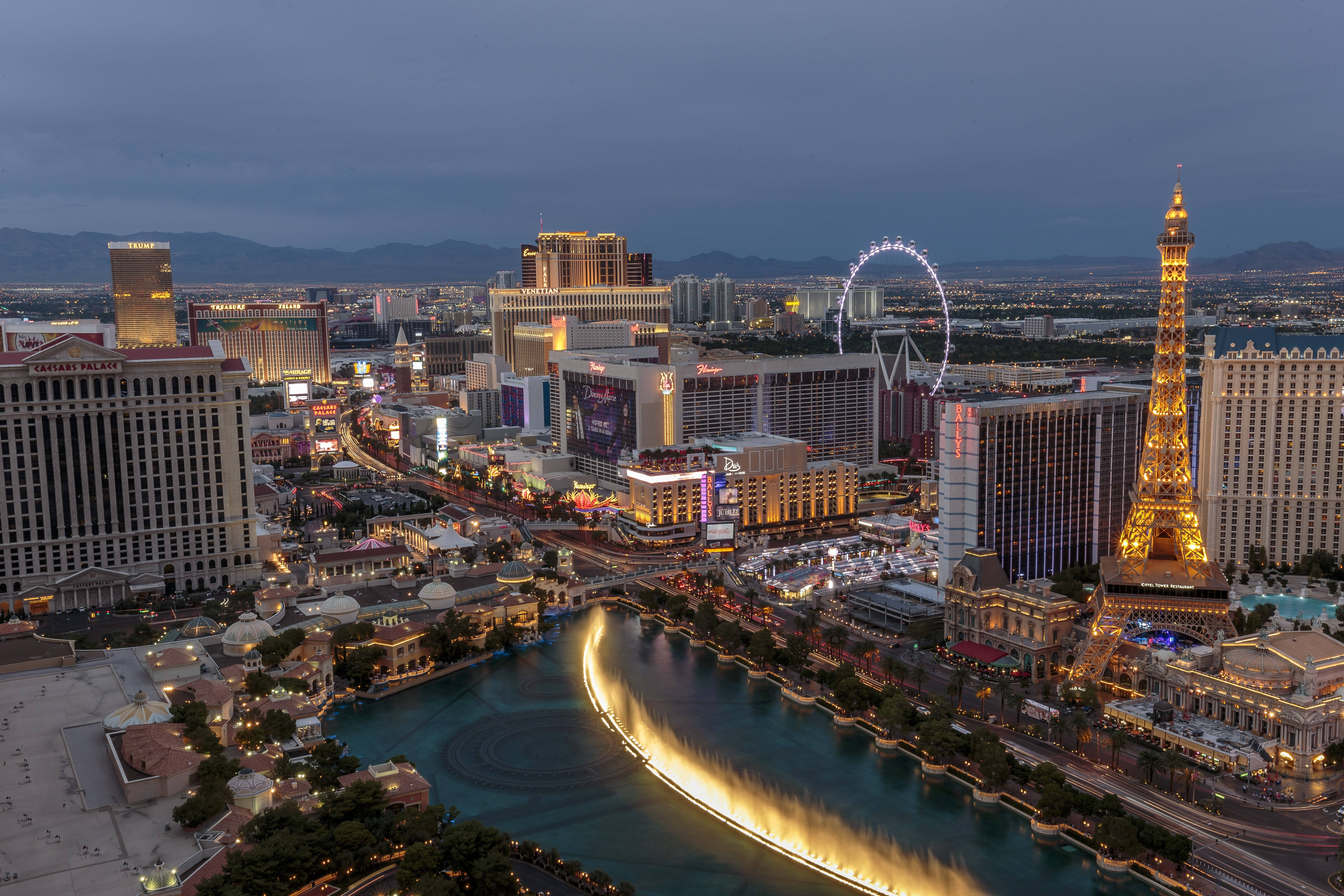 Las Vegas 4K 桌布 壁紙 — 黃昏時分拉斯維加斯的鳥瞰圖，燈火通明的飯店、噴泉和艾菲爾鐵塔複製品在漸暗的天空中閃耀。
