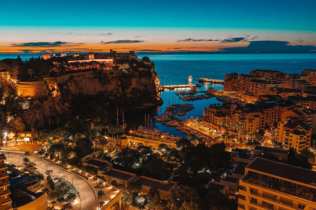 Monaco 桌布 壁紙 — 黃昏時分摩納哥的鳥瞰圖，發光的城市燈光反射在港口和俯瞰海洋的懸崖上。
