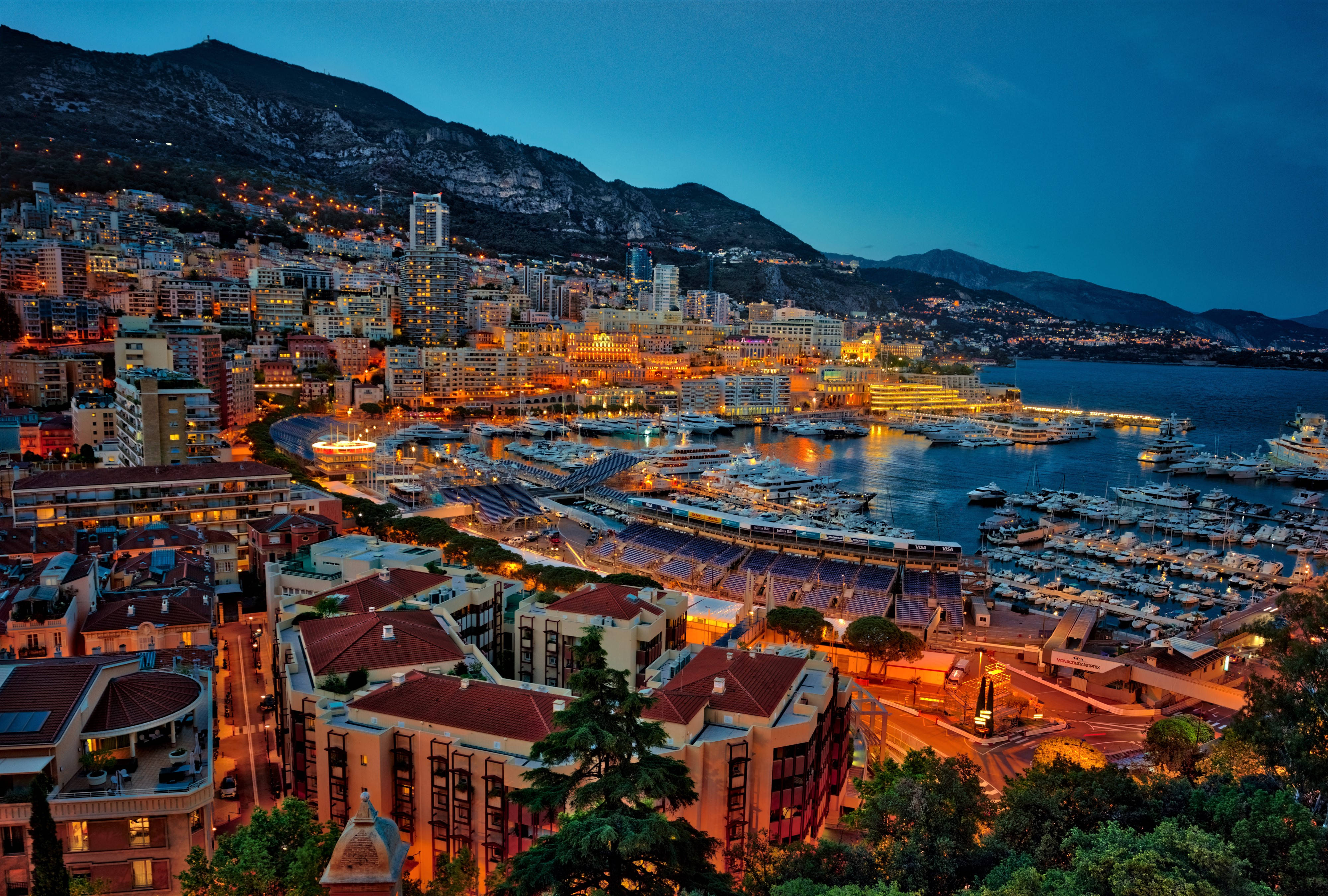 Monaco 桌布 壁紙 — 黃昏時分摩納哥的鳥瞰圖，發光的城市燈光反射在停滿遊艇的港灣上。