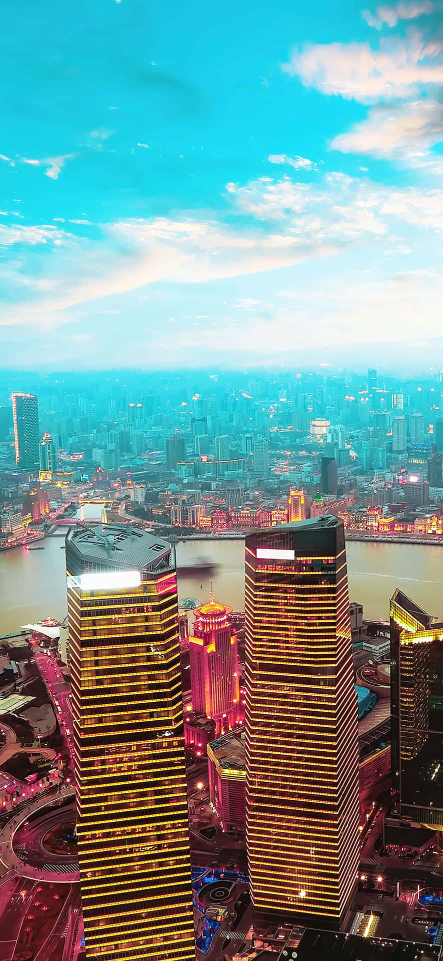 Shanghai City Skyline At Night 4K Phone Wallpaper 壁紙 — 黃昏時分未來城市景觀的鳥瞰圖，高聳的摩天大樓在金色和粉紅色的燈光中閃耀，映襯著充滿活力的藍綠色天空。