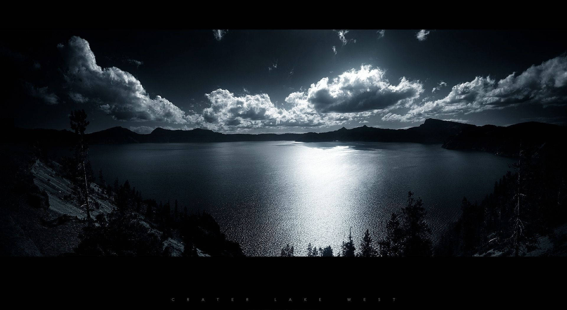 桌布 壁紙 — 黃昏時分火山口湖的戲劇性黑白全景，陽光照射的雲彩倒映在水面上。