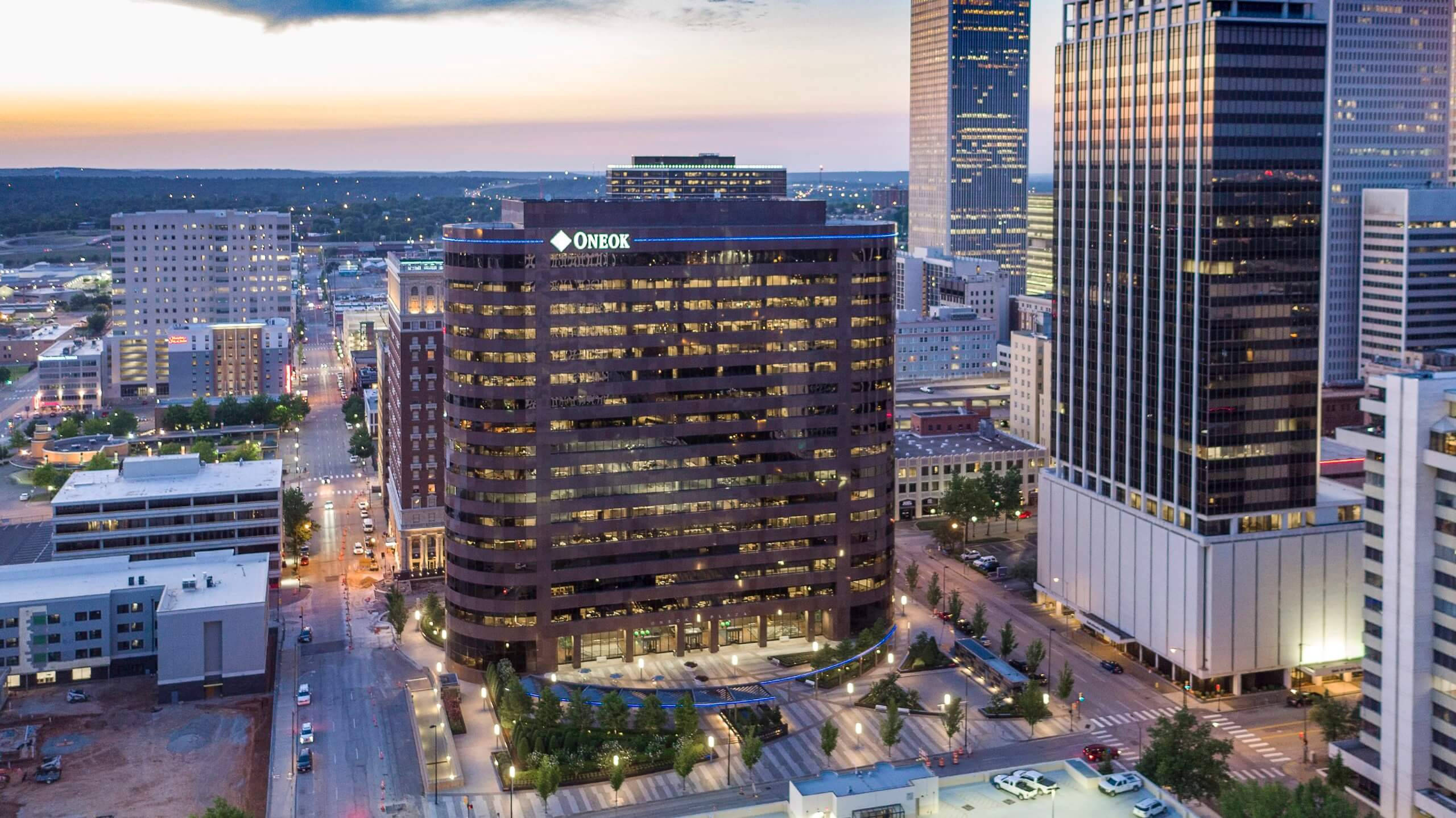 Oklahoma 桌布 壁紙 — 黃昏時分現代城市景觀的鳥瞰圖，摩天大樓和Oneok大樓在柔和的橙色天空中閃耀。
