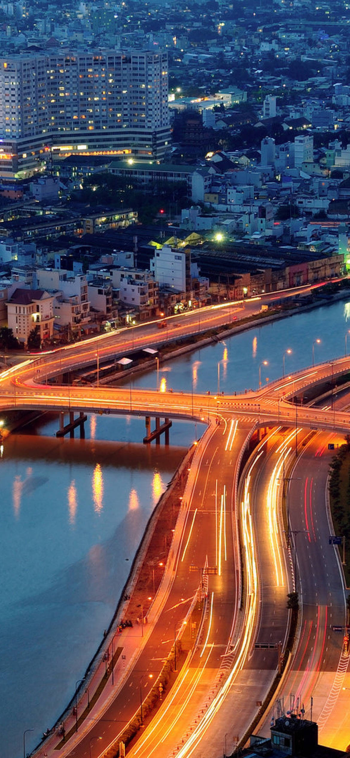 Ho Chi Minh City 桌布 壁紙 — 黃昏時分發光的城市高速公路的鳥瞰圖，河流上有光跡和燈火通明的建築物。