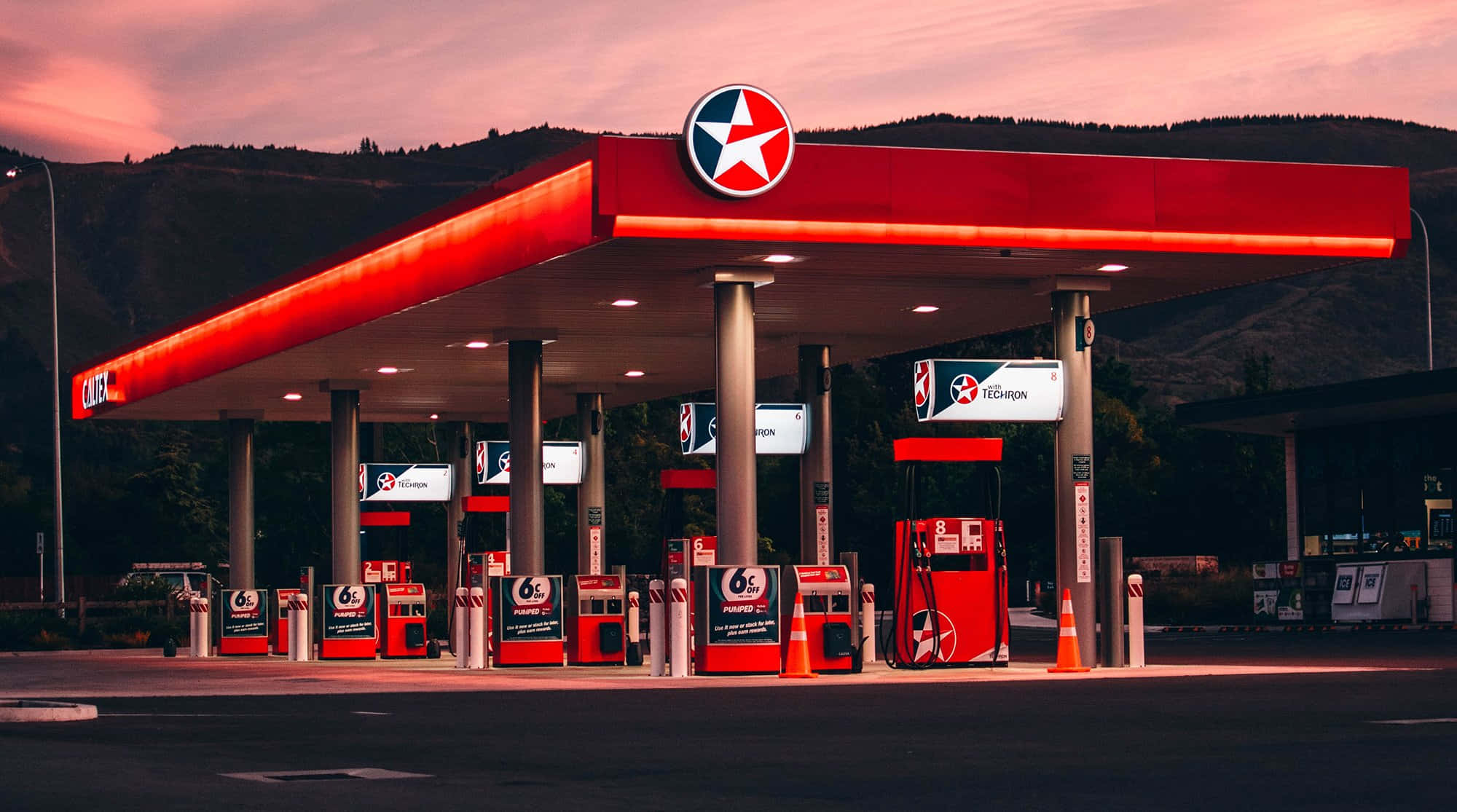 Petrol Station 桌布 壁紙 — 黃昏時分的Texaco加油站，紅色發光油泵和星星標誌襯托著粉紅和橙色的天空。