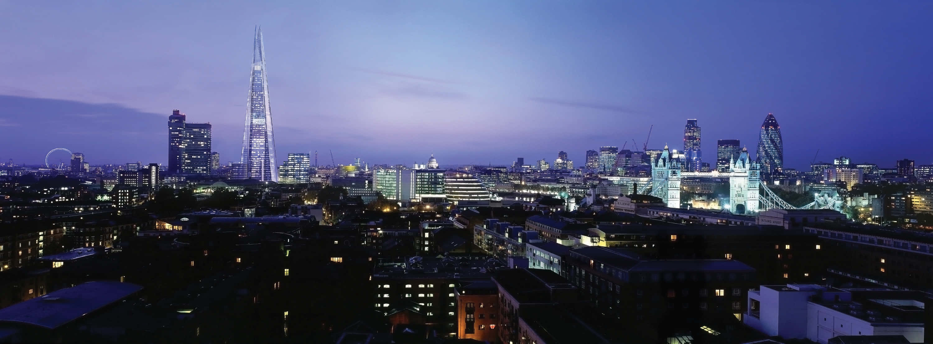 City At Night 桌布 壁紙 — 黃昏時分的倫敦天際線，在深紫色天空下，閃爍的摩天大樓和塔橋熠熠生輝。