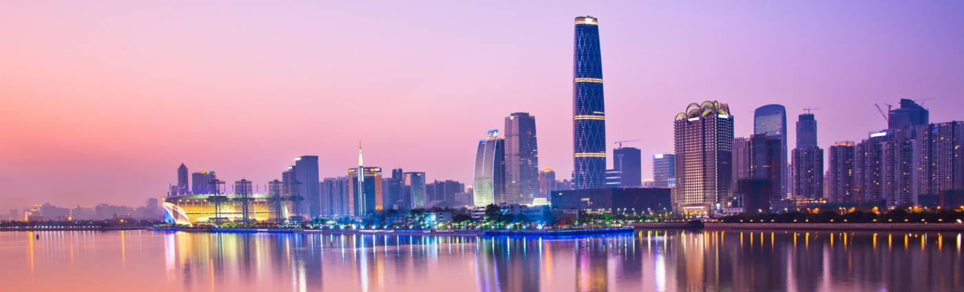 View 桌布 壁紙 — 黃昏時分的全景城市天際線，發光的摩天大樓倒映在平靜的水面上，天空呈現粉紫色。
