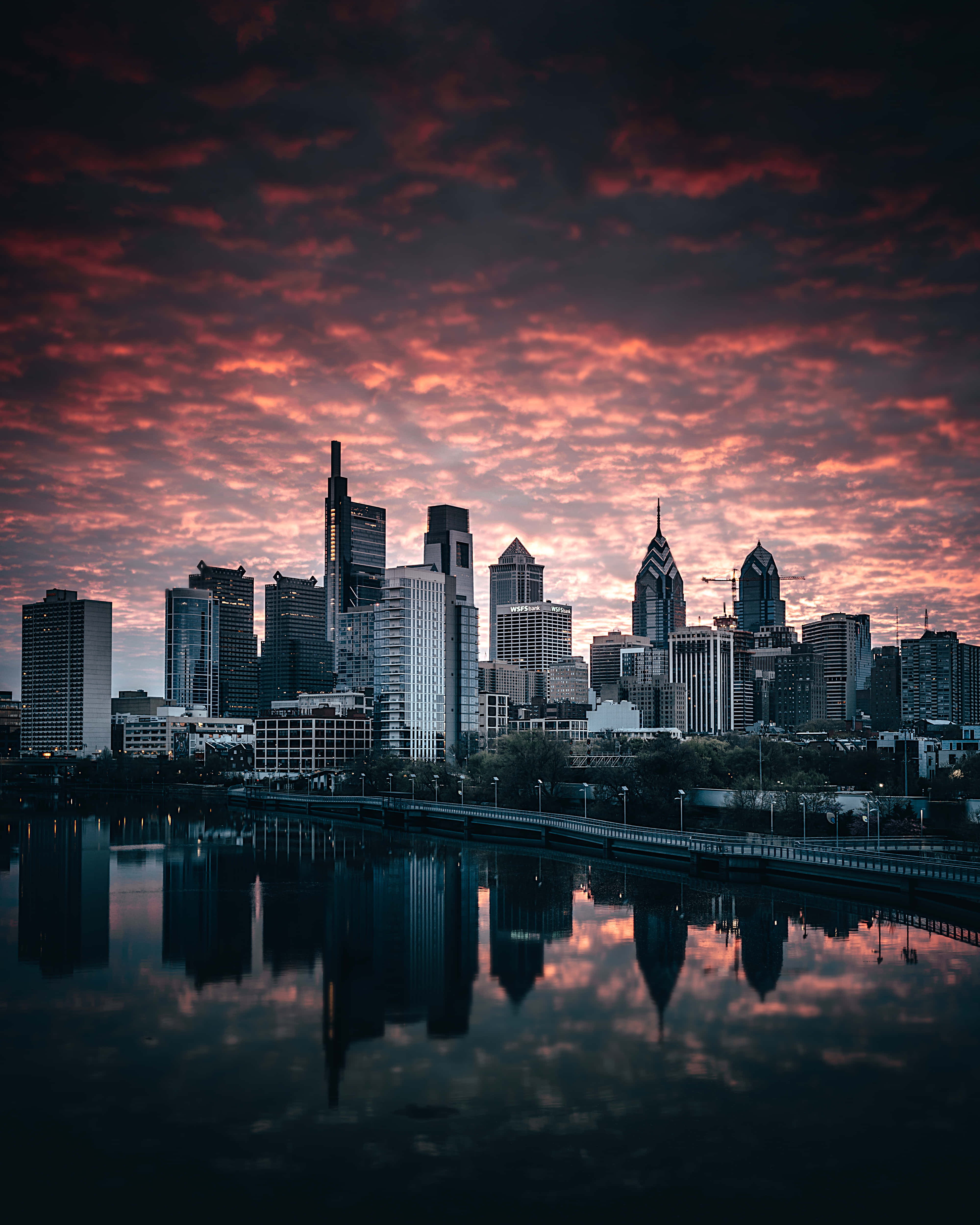 Philly 桌布 壁紙 — 黃昏時分的城市天際線，火紅的雲彩倒映在下方平靜的水面上。