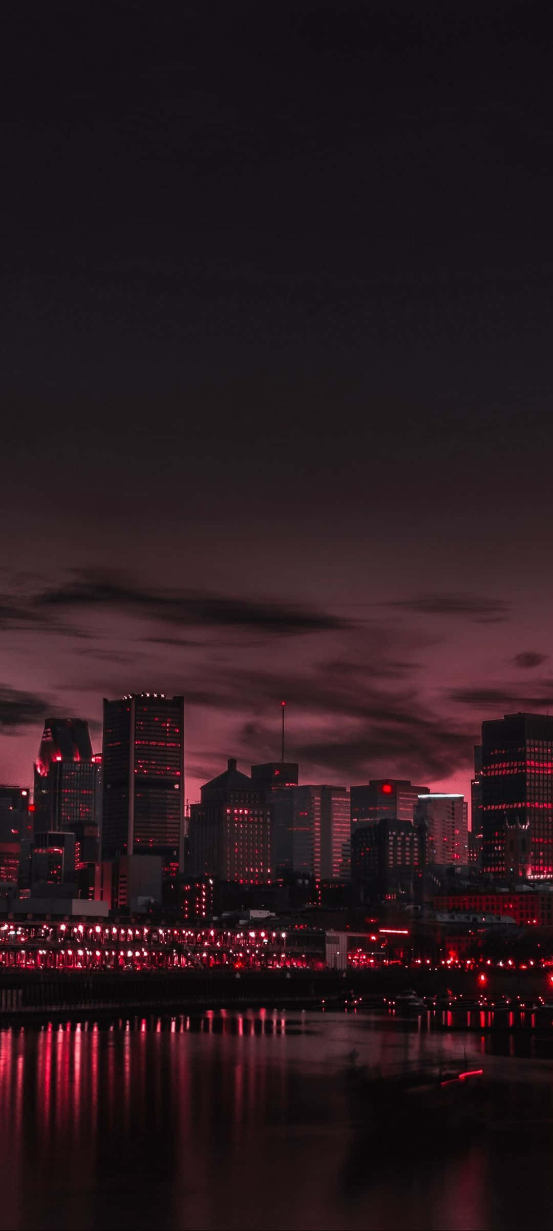City Night 桌布 壁紙 — 黃昏時分的城市天際線沐浴在深紅色的光芒中，倒影在水面上閃爍。