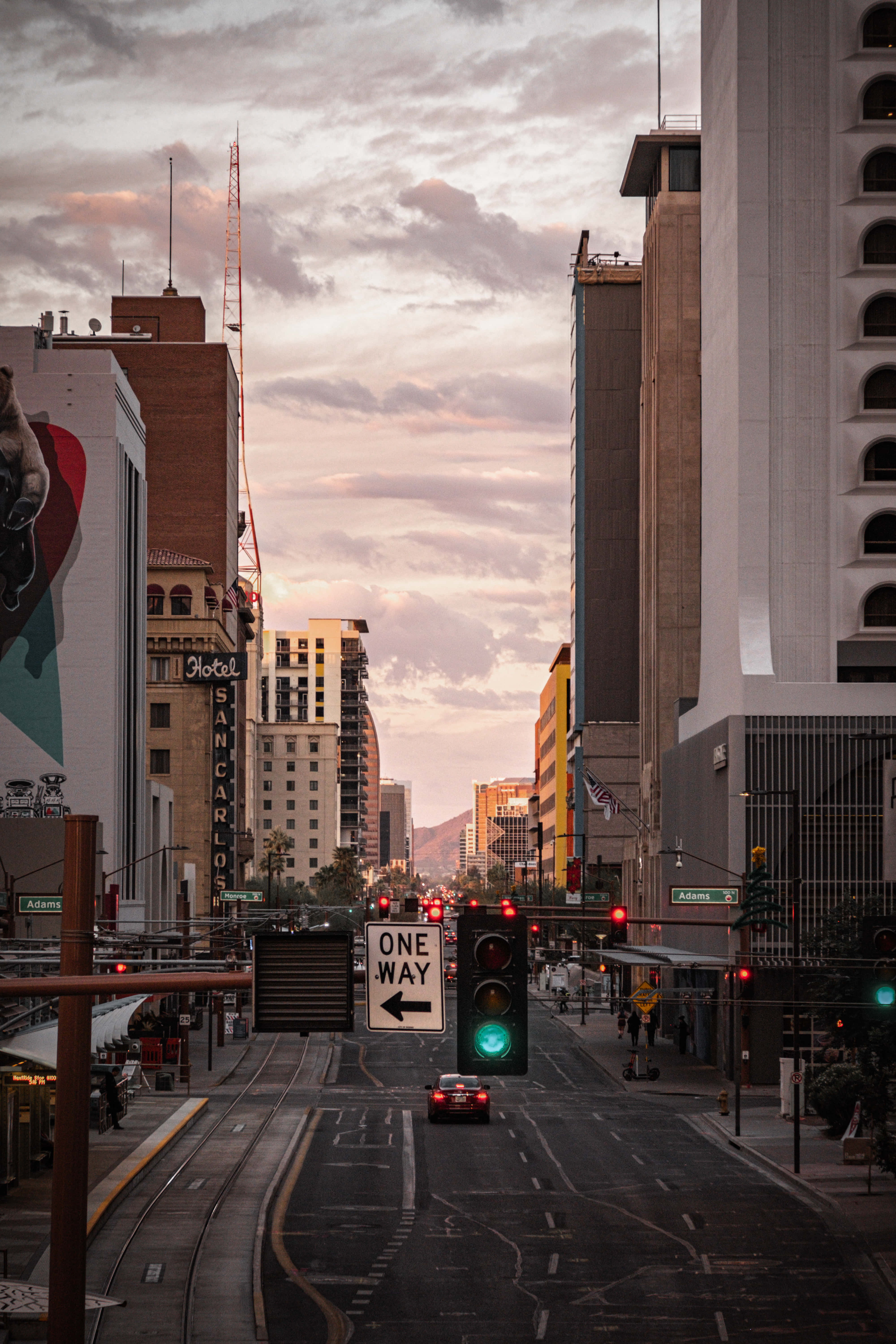 Phoenix Arizona 桌布 壁紙 — 黃昏時分的城市街道，高樓大廈，閃爍的綠色交通燈，以及一輛孤獨的汽車在路上行駛。
