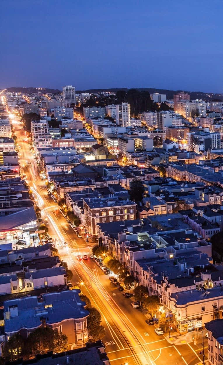 Android San Francisco 桌布 壁紙 — 黃昏時分的城市鳥瞰圖，發光的街燈和交通軌跡照亮了城市景觀。