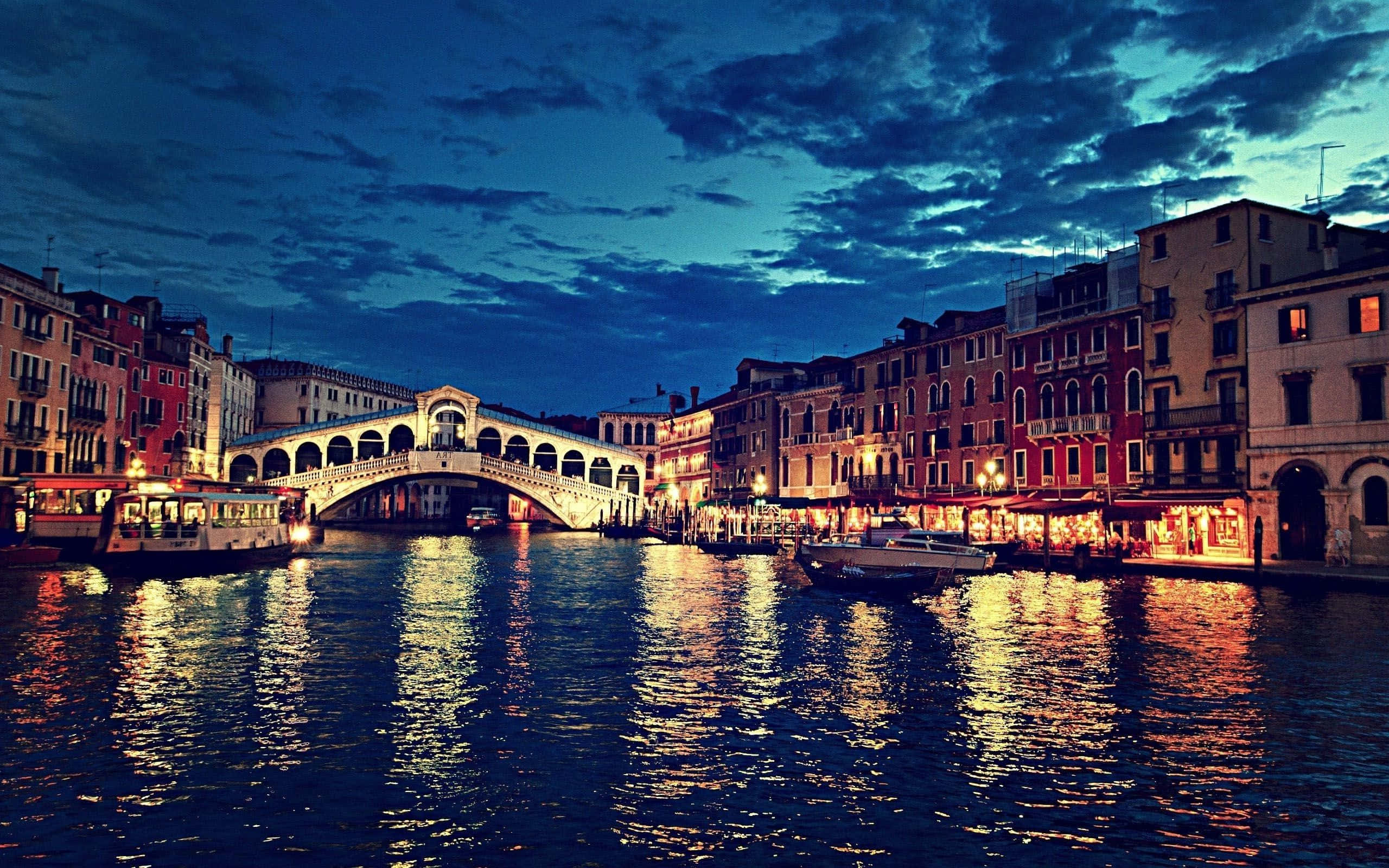 Italy Aesthetic 桌布 壁紙 — 黃昏時分的威尼斯，歷史建築環繞的運河中映照著燈火通明的里亞爾托橋。